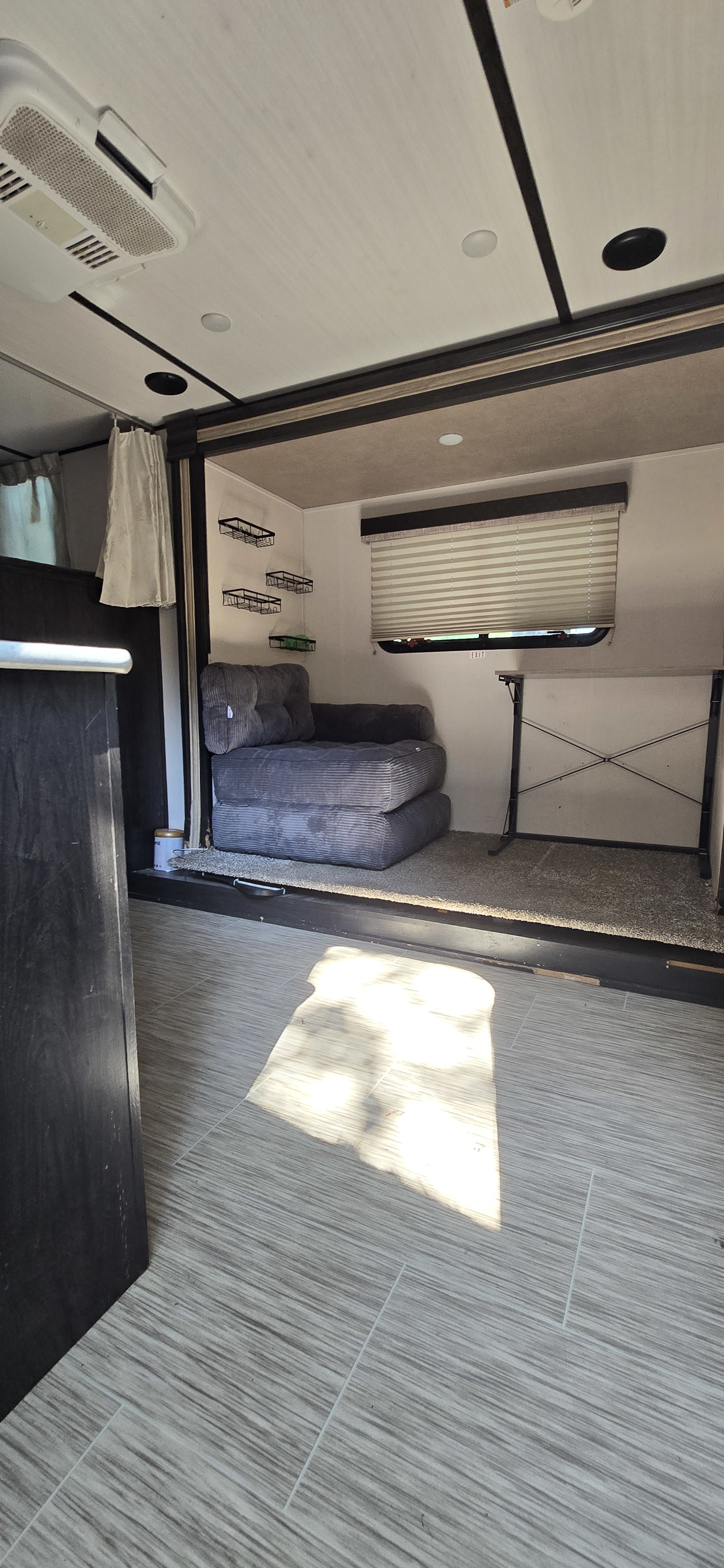 This RV rental offers a flexible living space: a modular sofa, fold-down table, AC, and mixed flooring (tile/carpet).. Forest River Surveyor Legend 2020