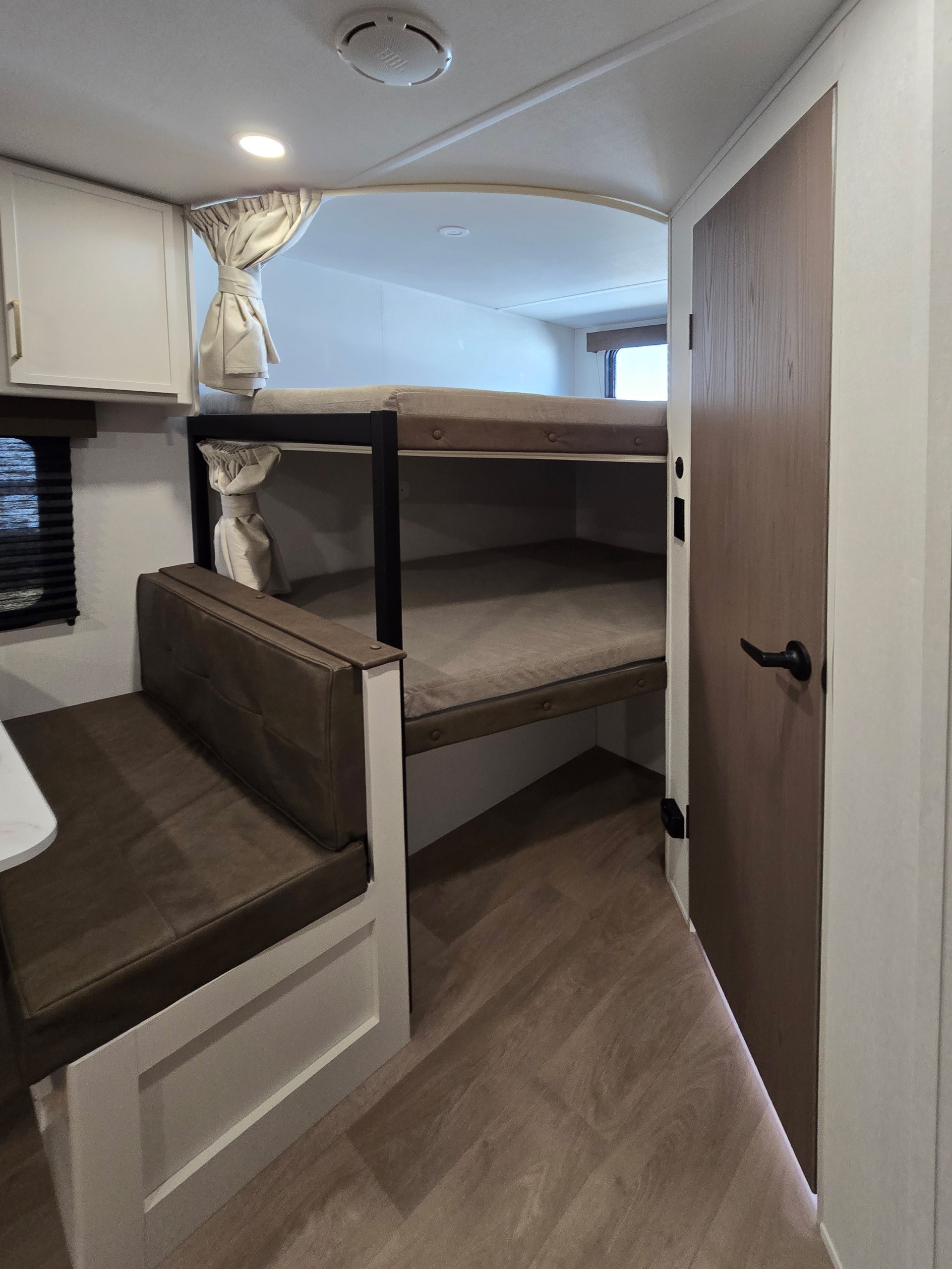 Functional rv rental interior featuring bunk beds, a dining booth, and a door for private spaces.. Grand Design Transcend Xplor 2026