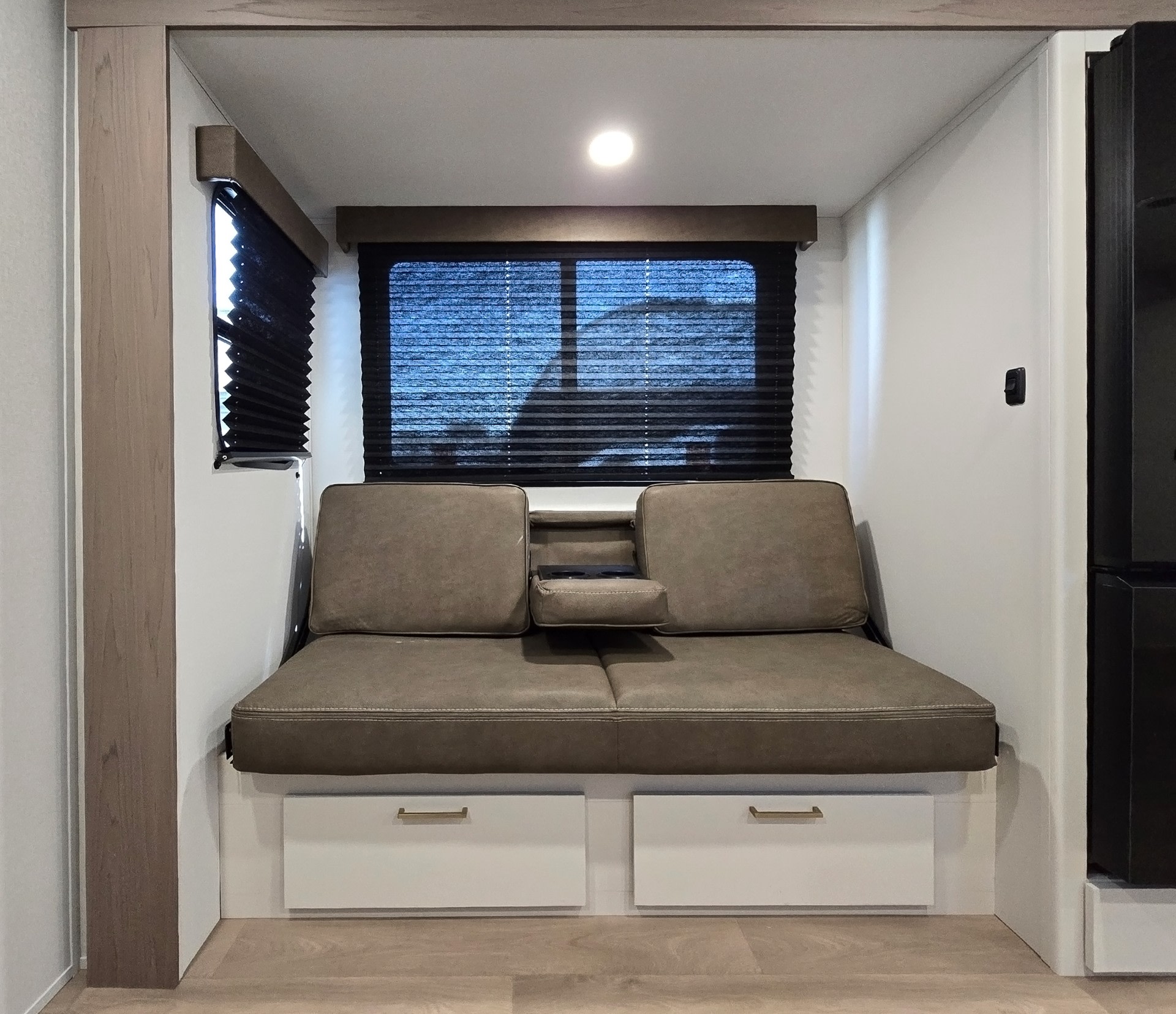 Cozy RV rental interior with a comfortable sofa, pull-down console, windows with blinds, and under-seat storage drawers.. Grand Design Transcend Xplor 2026