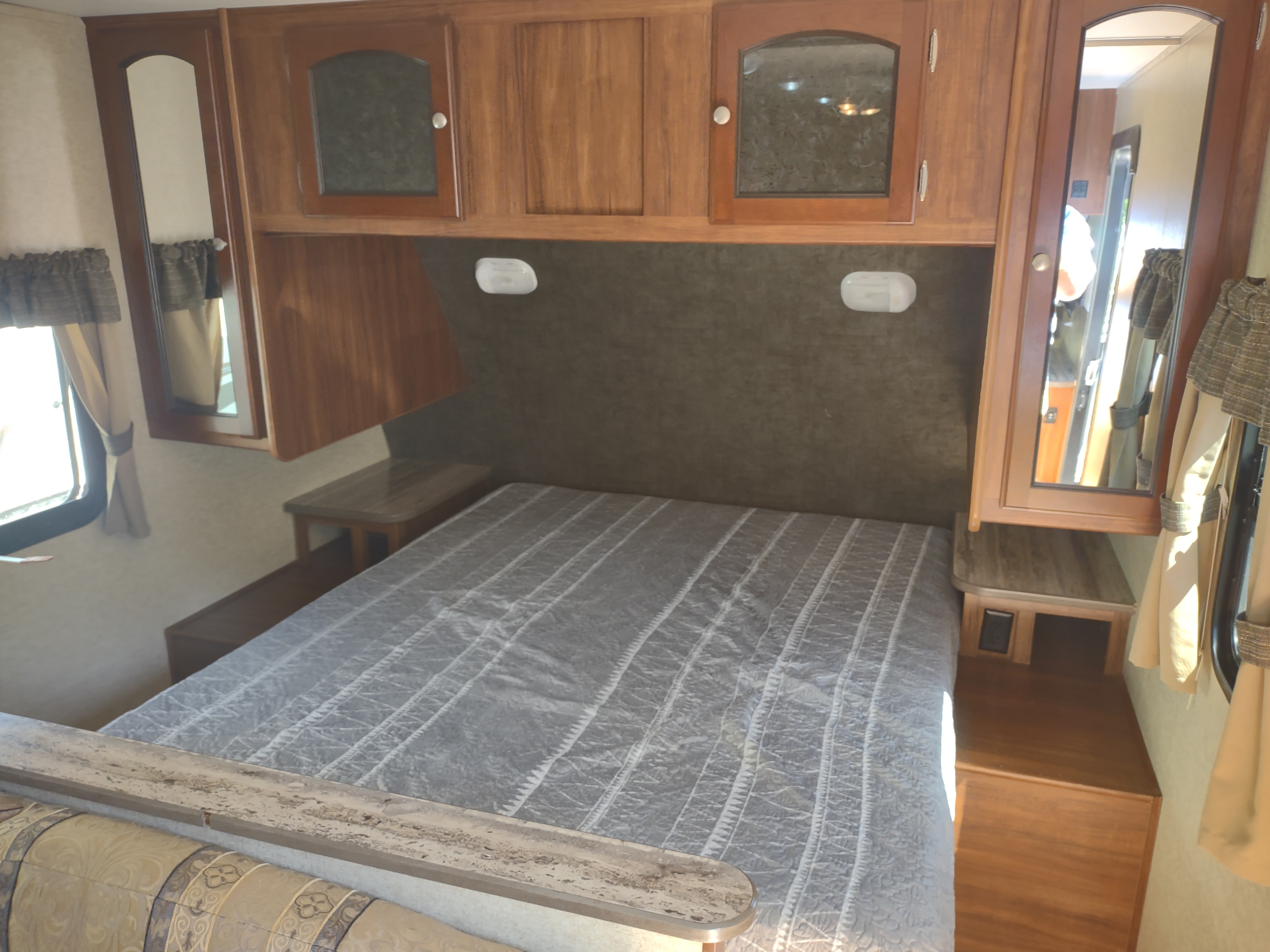 Spacious RV rental bedroom with comfortable bed, overhead storage, and dual nightstands, ready for your next adventure.. Heartland RVs North Trail 2014