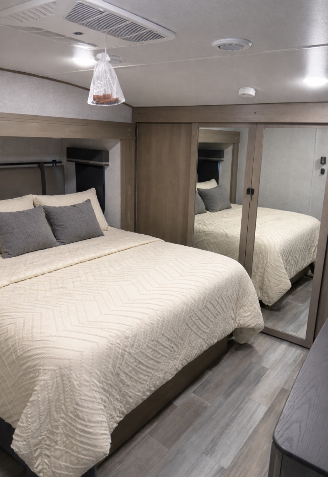 RV rental bedroom featuring a comfy bed, modern mirrored closet, gray flooring, and overhead AC. A cozy, functional space.. Grand Design Reflection 2023