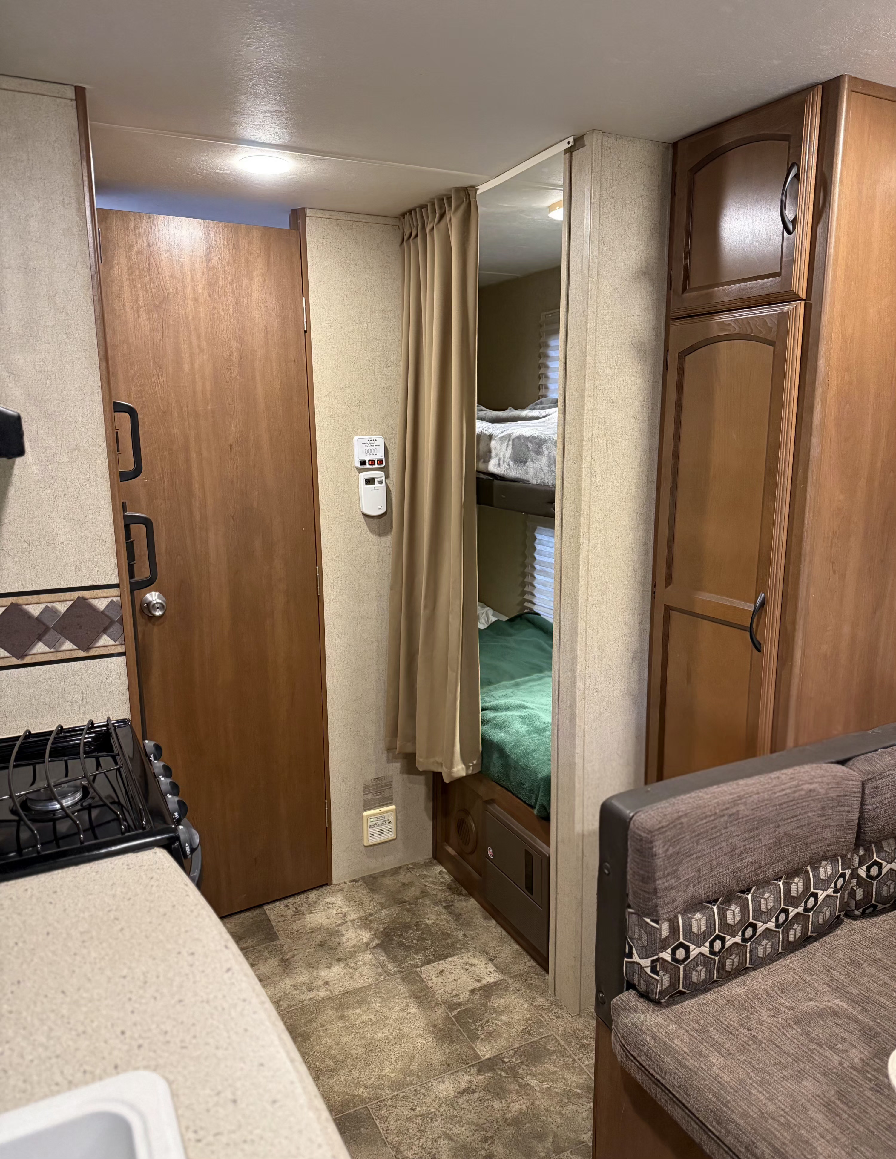 This RV rental shows a compact interior with bunk beds, a kitchen counter and stove, and a dining booth in muted tones.. Forest River Coachmen Freedom Express 2015