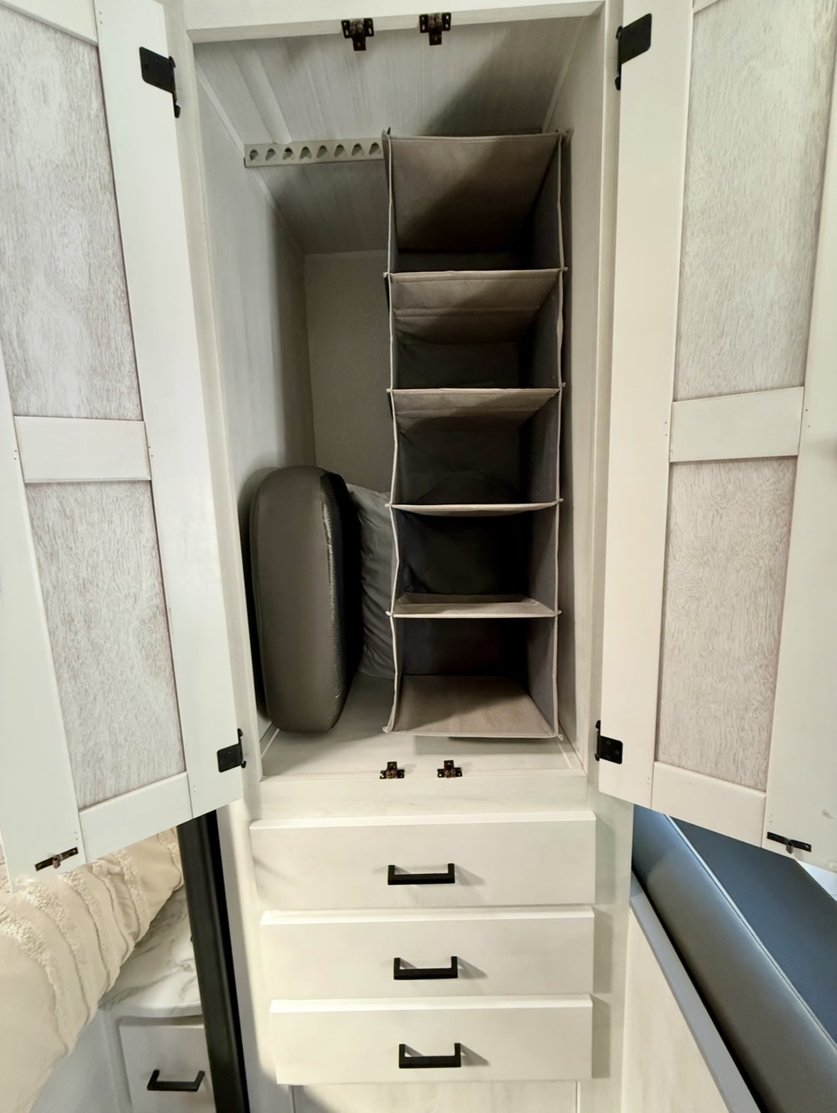 Organized RV rental closet with a hanging rack, multi-tier fabric shelves, three drawers, and storage for essentials.. East to West Entrada 2024