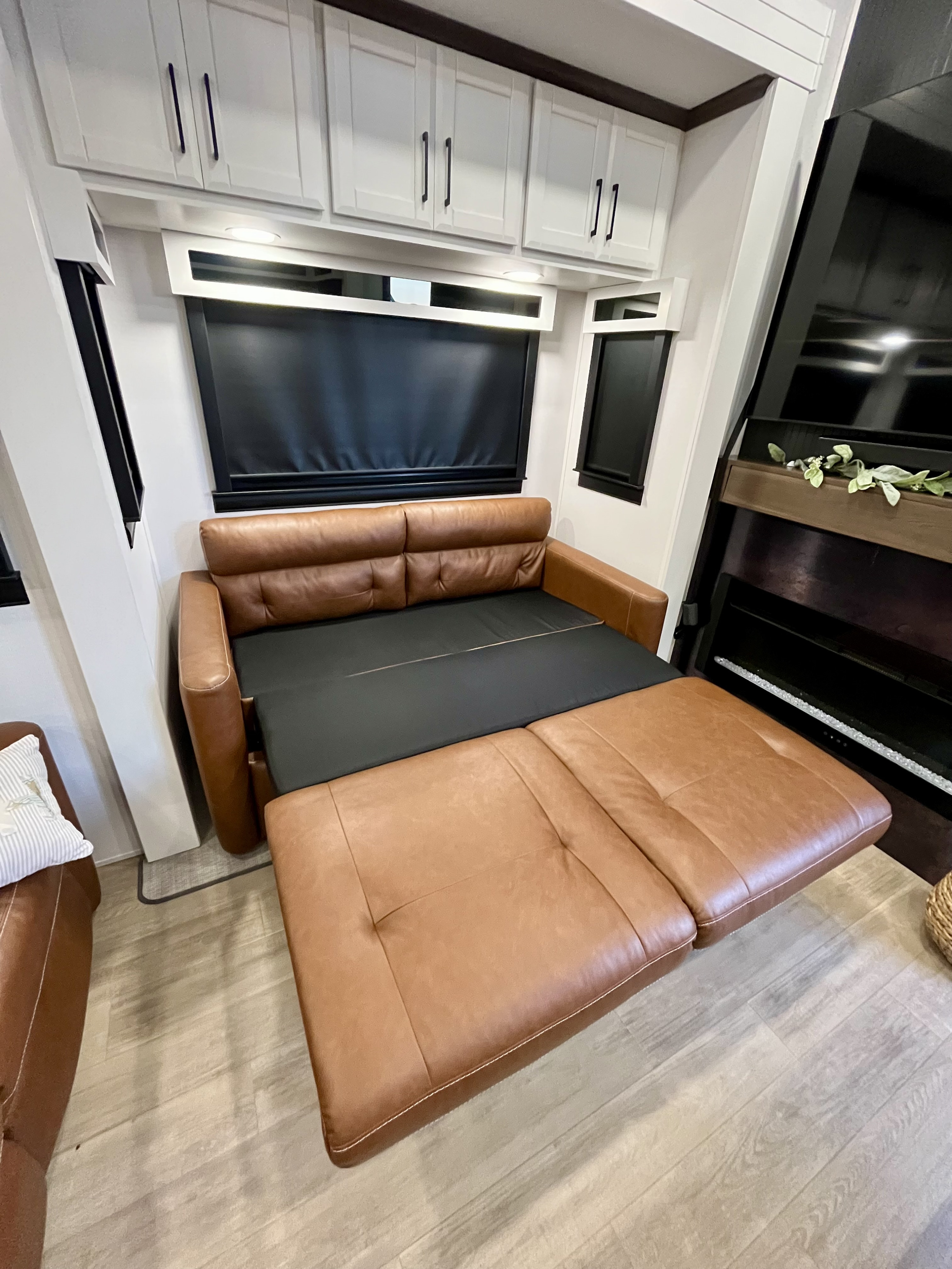 RV rental: Brown leather sofa bed partially extended, showing its sleeping function in a modern interior.. Forest River 39RKFB 2024