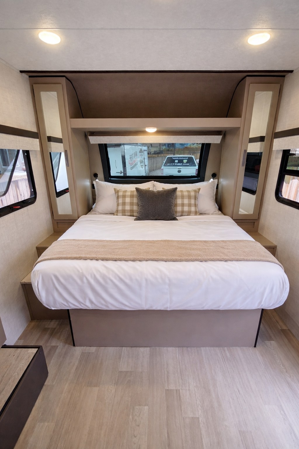 Bright RV rental bedroom with queen-sized bed, white linens, checkered pillows, and built-in shelving, ready for adventure.. KZ RV Connect Mini 2024