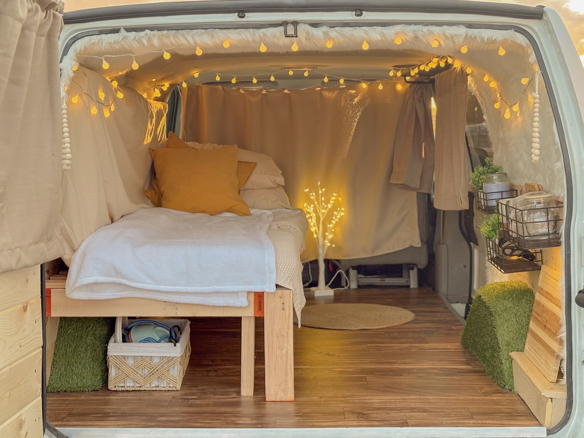 Cozy RV rental camper van interior. Features a comfy bed, string lights, wooden floors, and organized storage.. Chevrolet Astro 2005