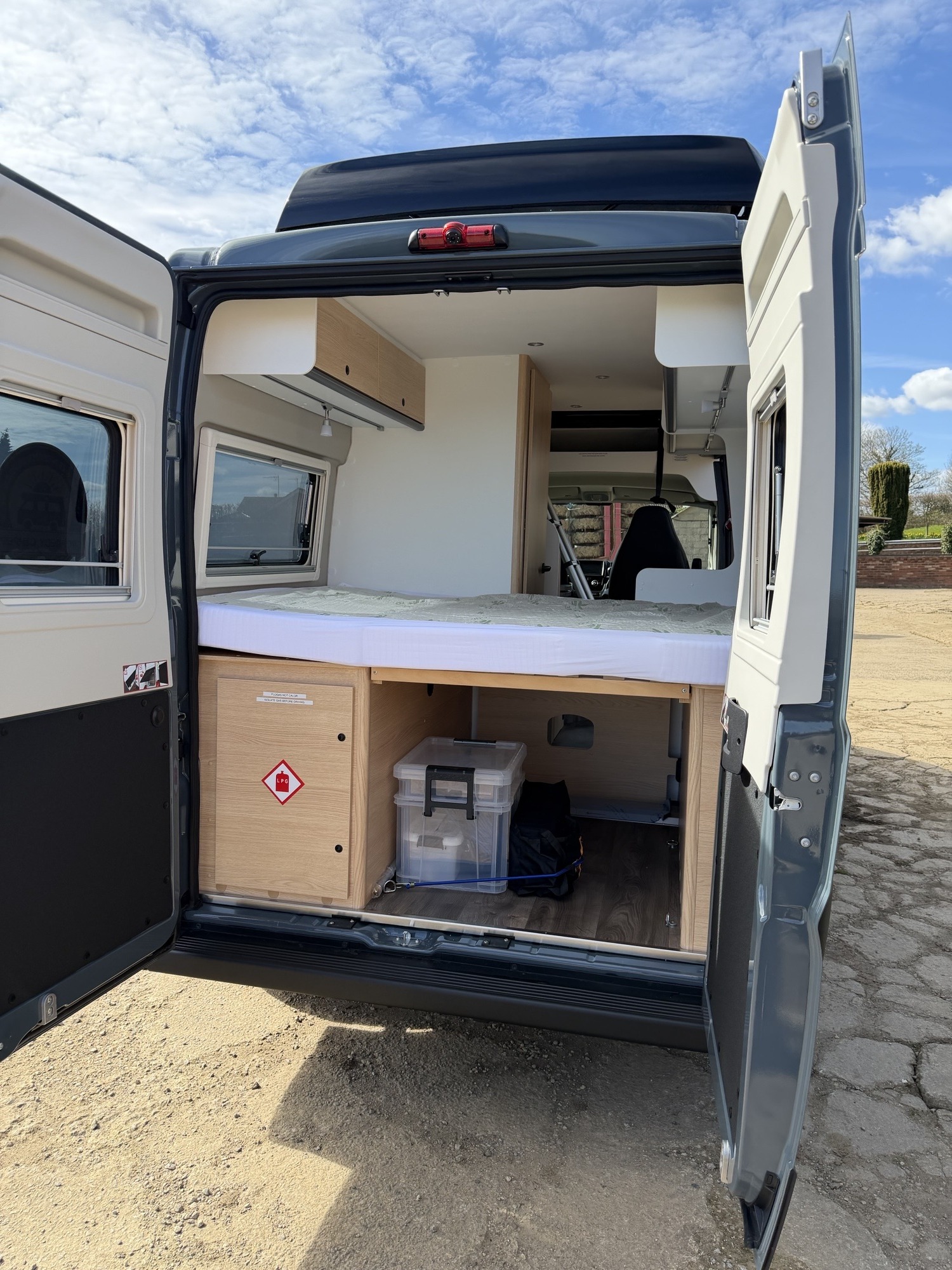 Spacious RV rental campervan interior with open back doors, revealing a comfy bed, windows, and practical storage for adventure travel.. Sunlight Cliff 600rt adventure 2026