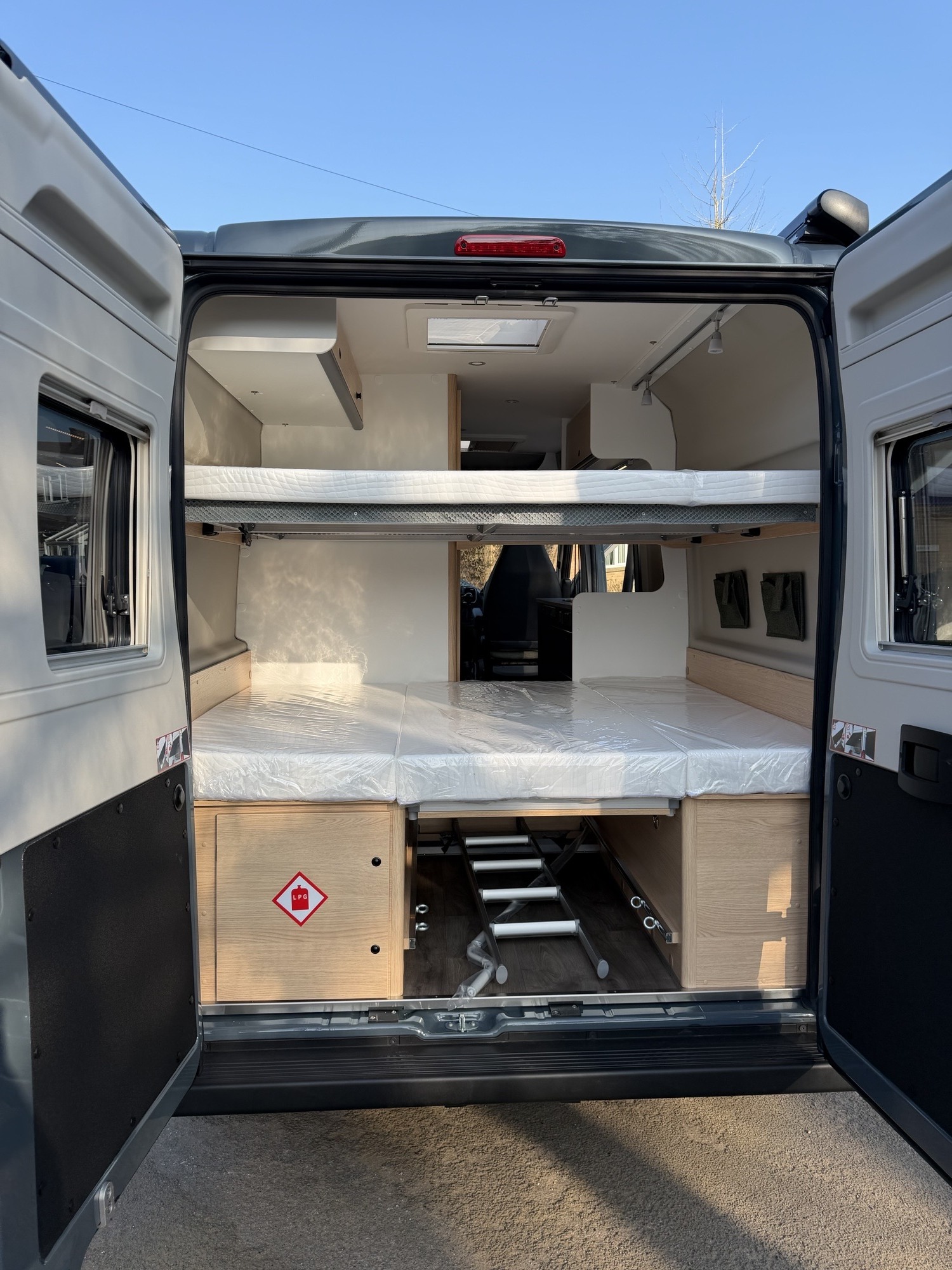 Inside this spacious rv rental camper van, two bunk beds, under-bed storage (with an LPG cabinet), and a stowed ladder are visible.. Sunlght Cliff 601 Adventure 2026