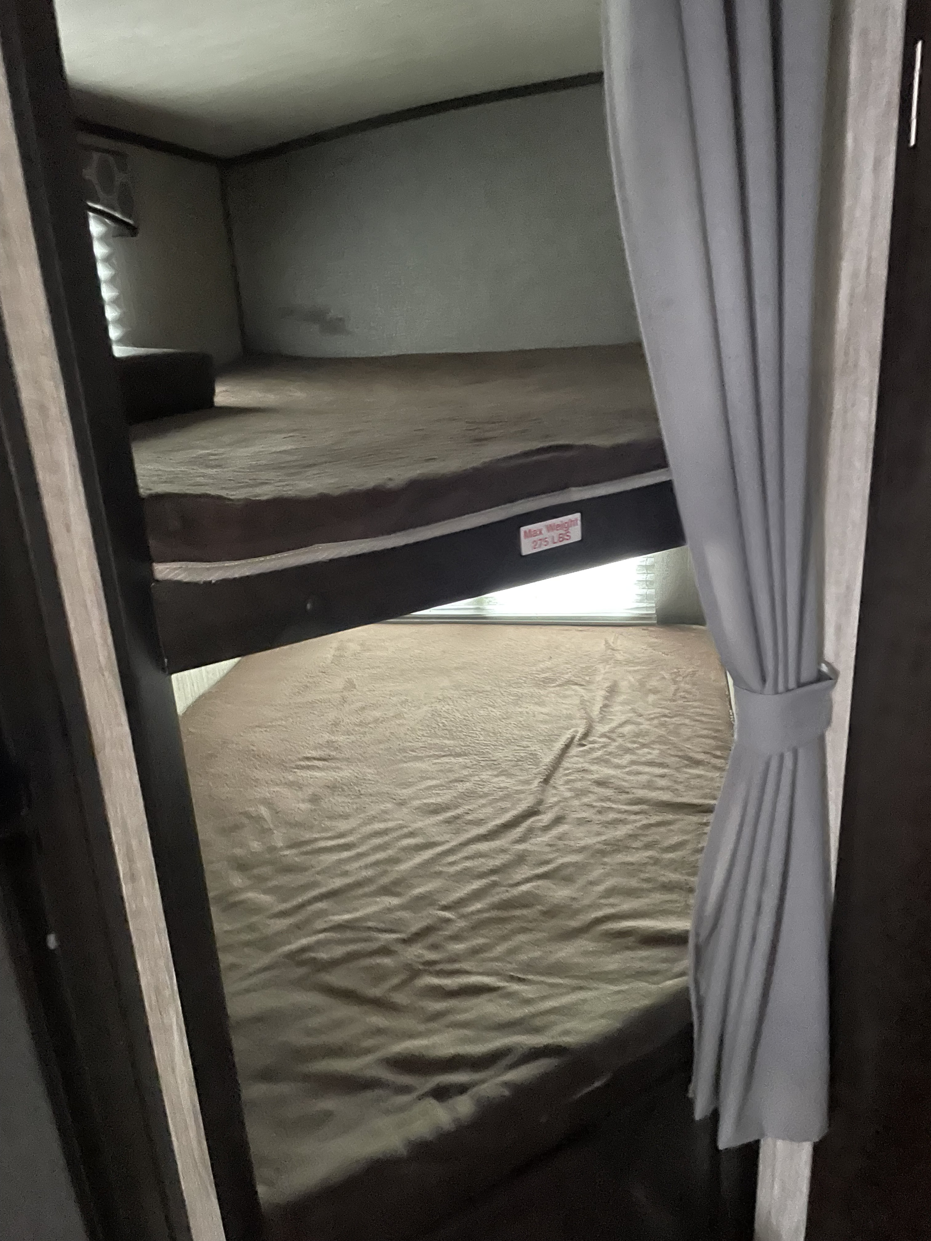 Compact bunk beds inside an RV rental, featuring a 275 lbs weight limit on the top bunk, with a privacy curtain.. Cruiser RV Shadow Cruiser 2019