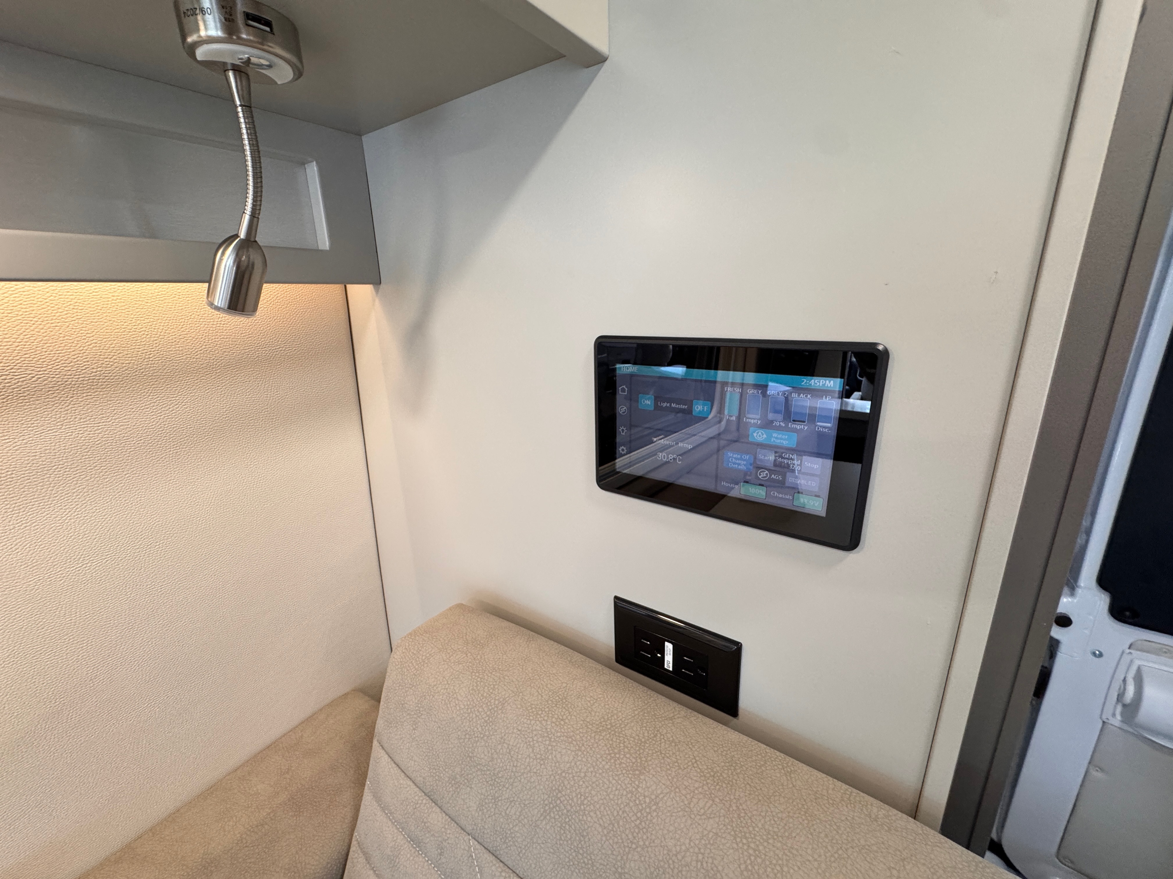 Inside an RV rental: a digital control panel, flexible reading light, outlets, and upholstered seating in a cozy space.. Forest River Coachmen Nova 2026
