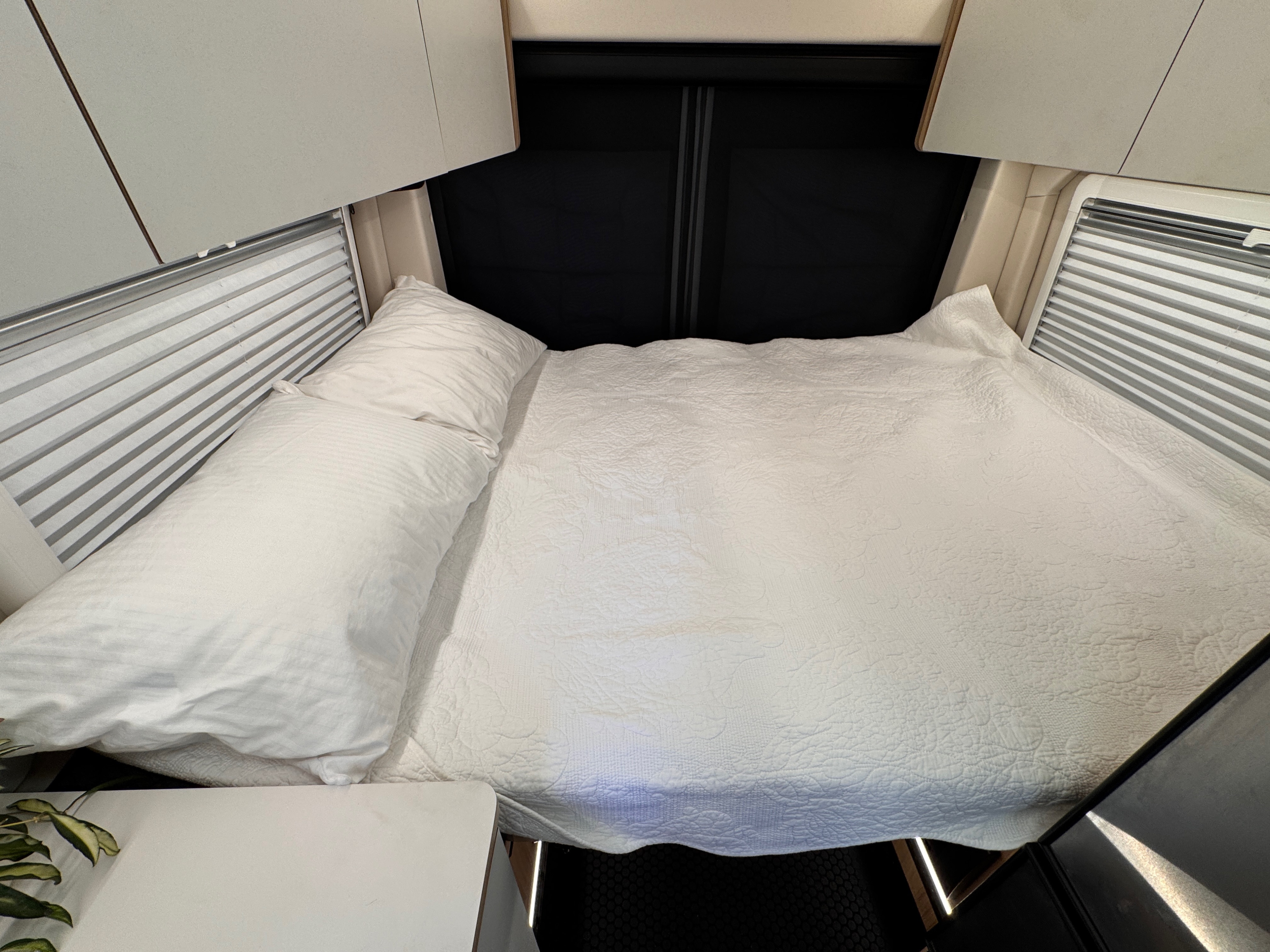 Cozy RV rental bed with fresh white linens, overhead cabinets, and window blinds for a comfortable sleep.. Forest River Coachmen Pixel 2026
