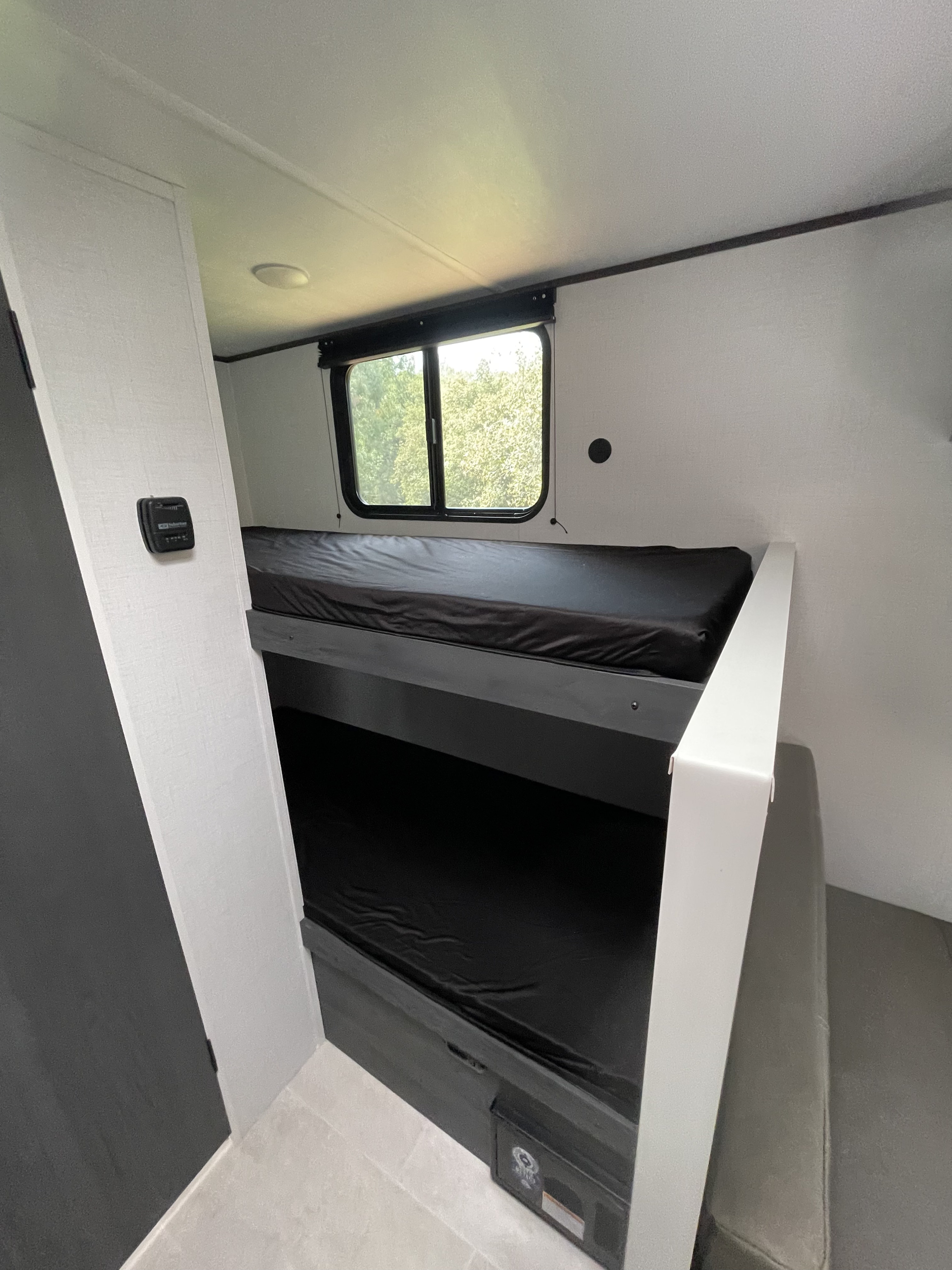 RV rental interior featuring modern bunk beds and a window. This offers a cozy sleeping setup for a camper adventure.. Aspen Trail 17BH 2026