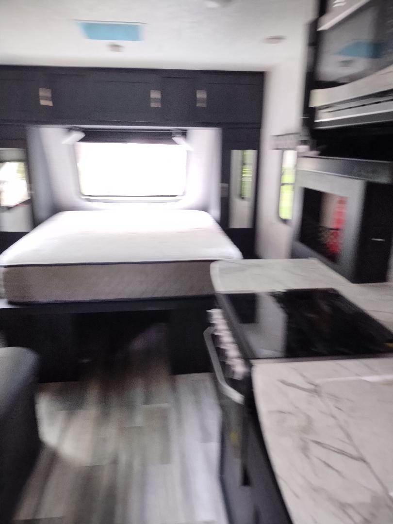 RV rental interior featuring a cozy bedroom with overhead storage, a bright window, and a compact kitchen area.. Forest River Coachmen Freedom Express Ultra Lite 2022