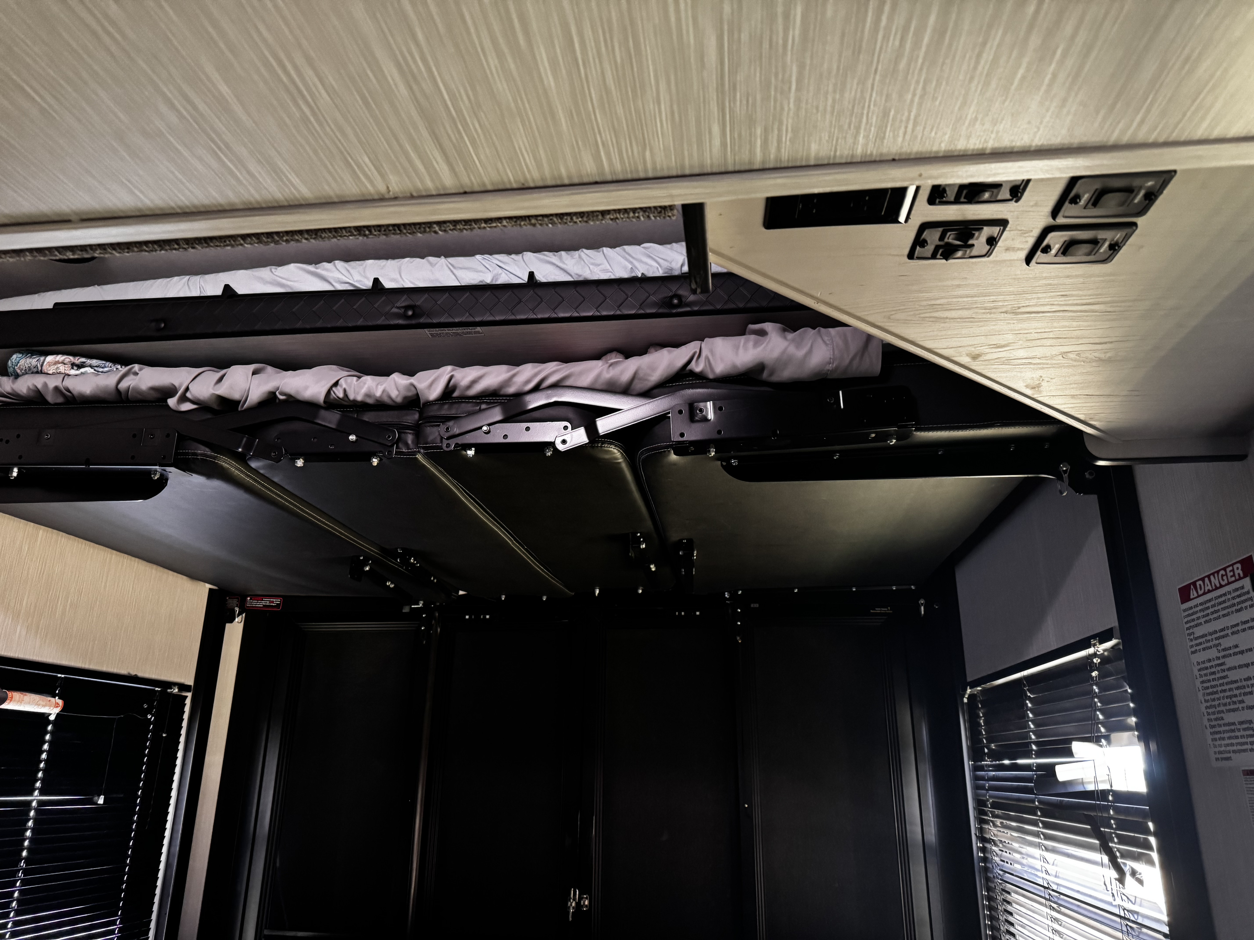 Inside an RV rental: a convertible bed/seating setup with a top bunk and controls, showcasing flexible living space.. Heartland Cyclone 2022
