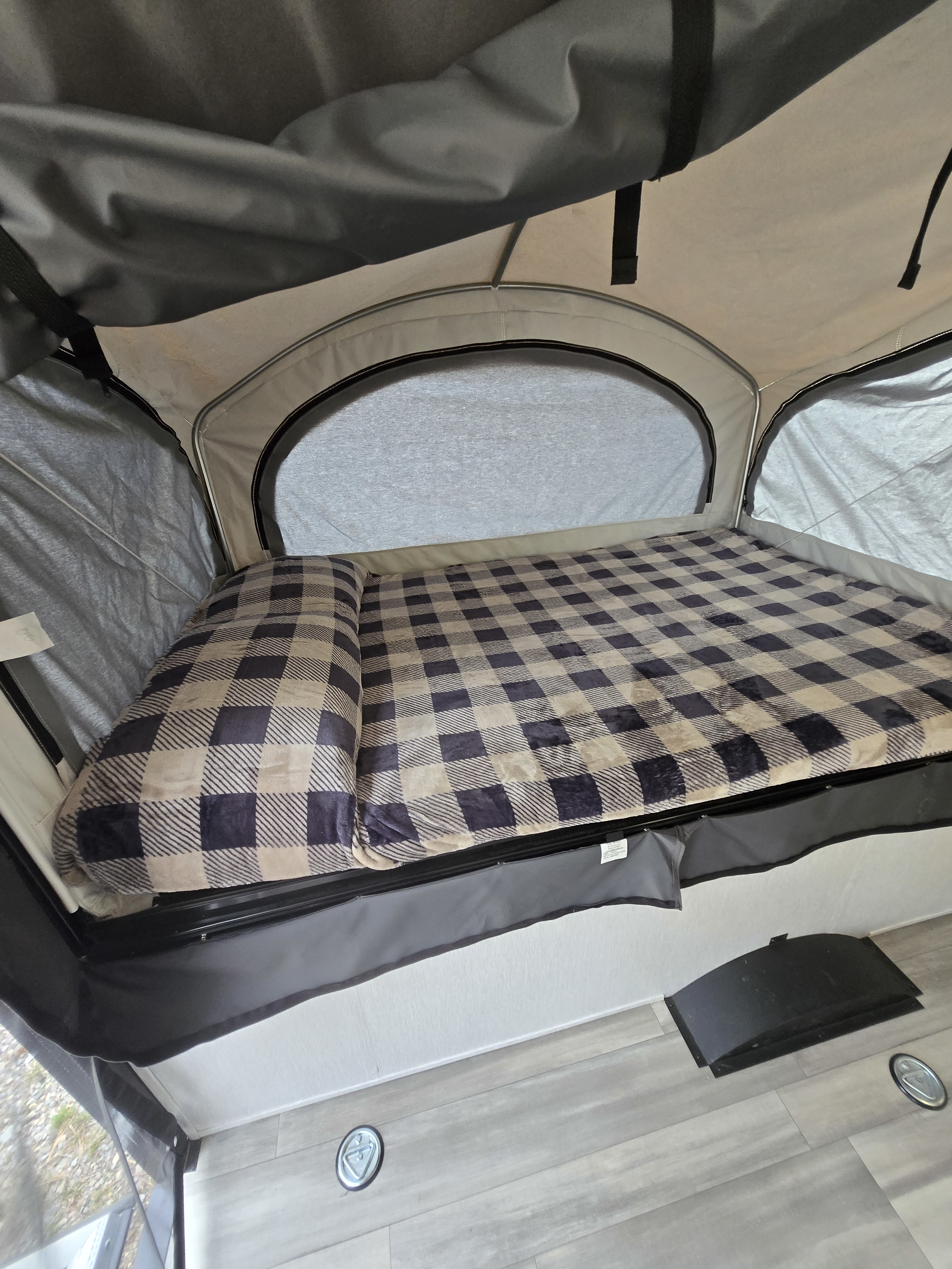 Cozy interior of an RV rental pop-up bed with a plaid blanket. A comfortable sleeping area for your camping adventure.. Wayfinder Go Lite Boulderback TH 2026