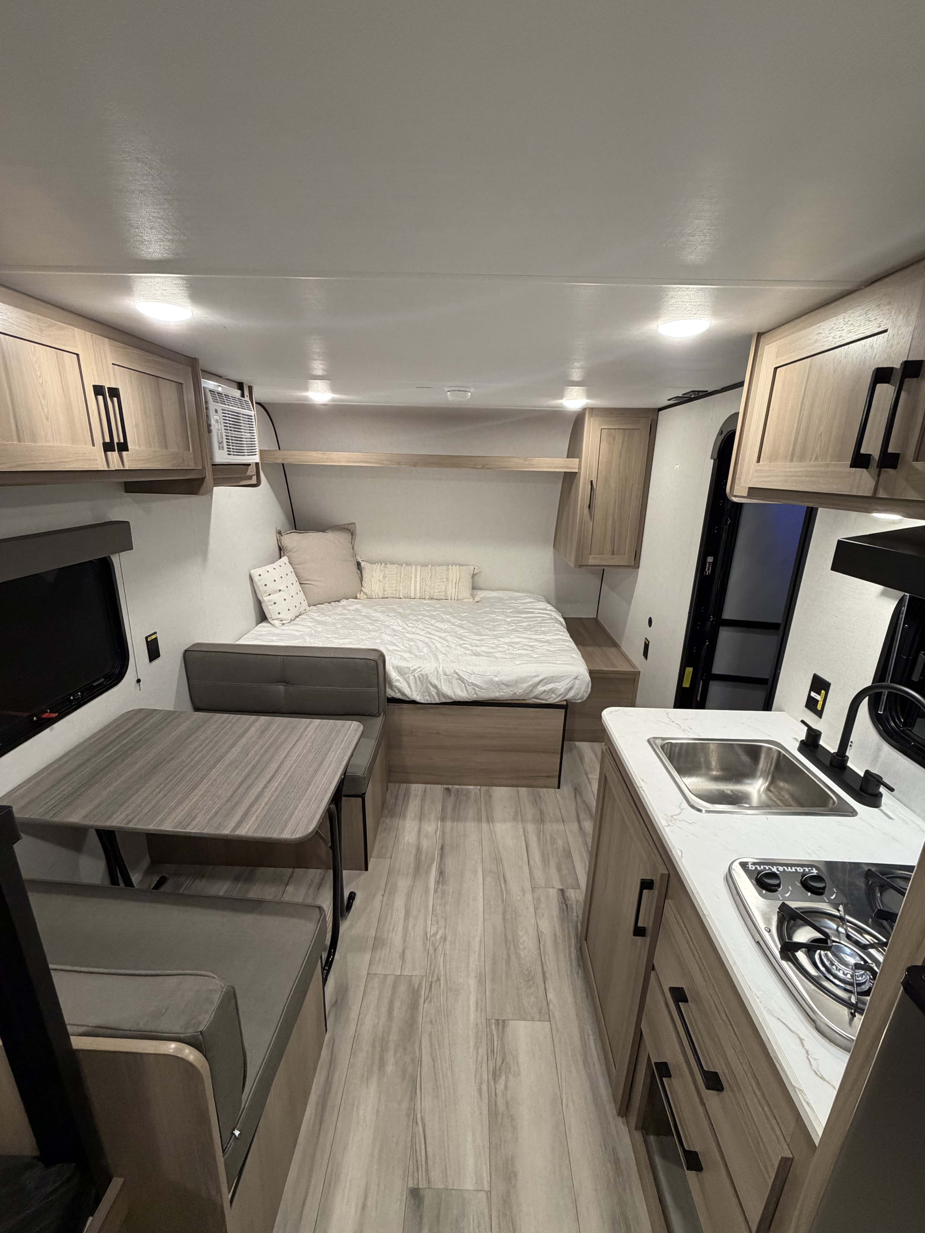 Bright, modern rv rental interior showcasing a bed, kitchen, and dinette with stylish wood accents.. Coleman 17B 2026