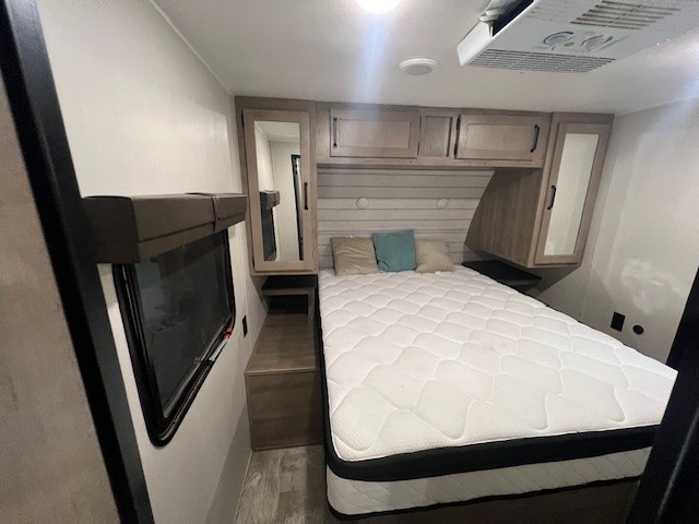 Cozy RV rental bedroom featuring a comfortable bed, overhead cabinets, and a window for a relaxing travel experience.. Forest River Palomino Puma 2024