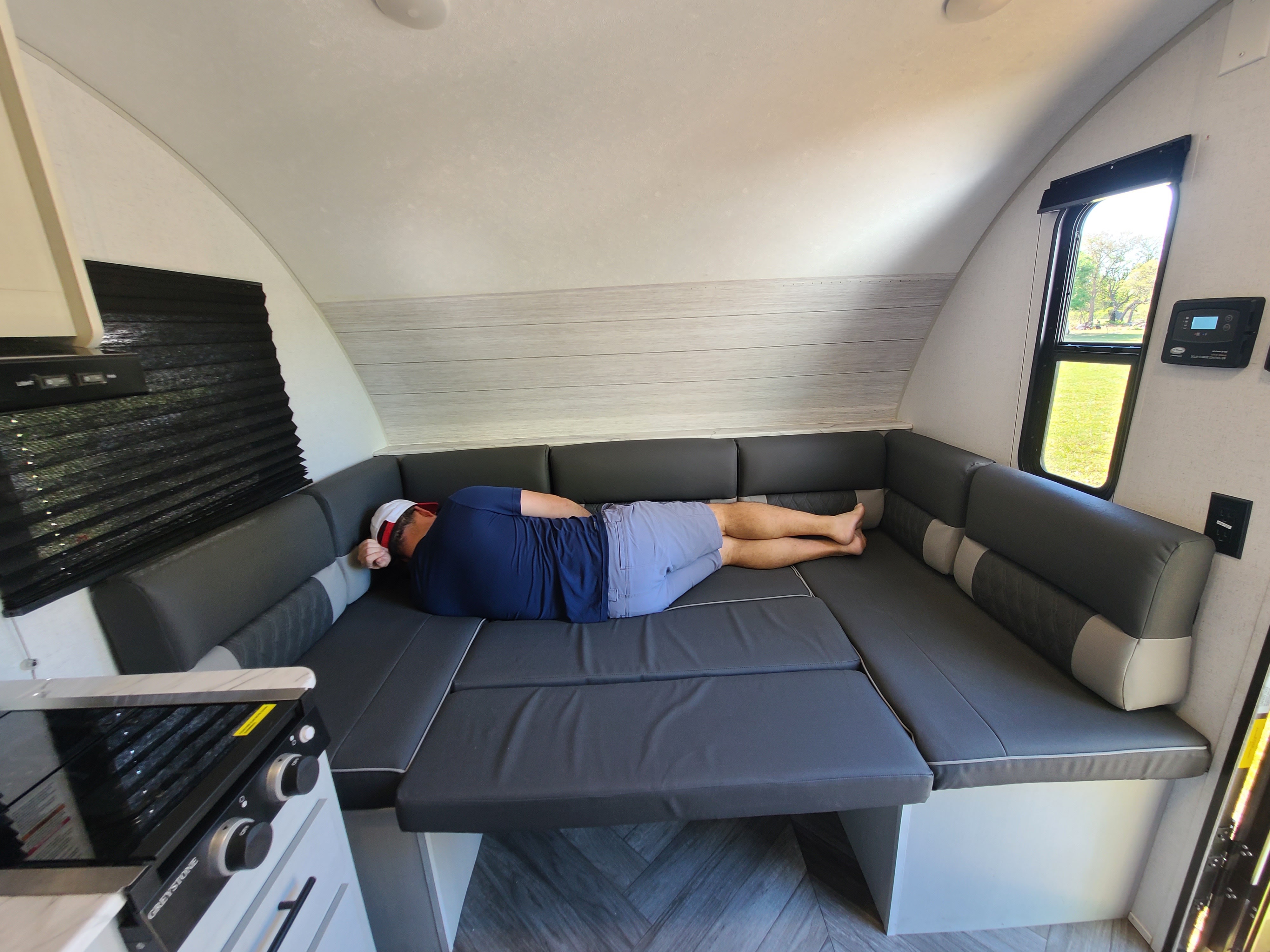 Relaxing in an RV rental: a person naps on the comfortable dinette-turned-bed inside a modern RV interior.. Forest River Salem FSX 2022