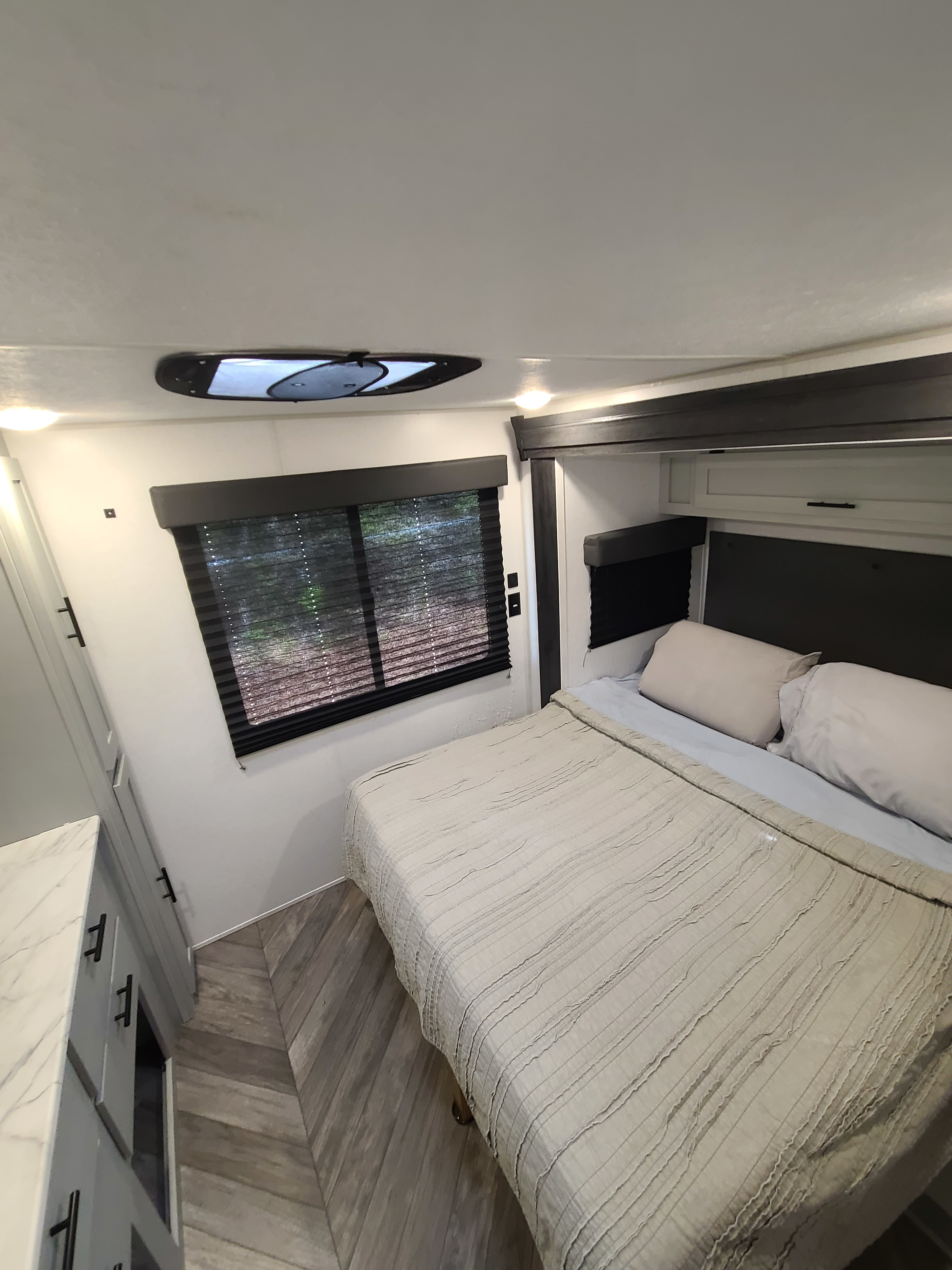 Modern RV rental bedroom with comfortable bed, window, and skylight. Perfect for your next adventure.. Forest River Salem FSX 2022