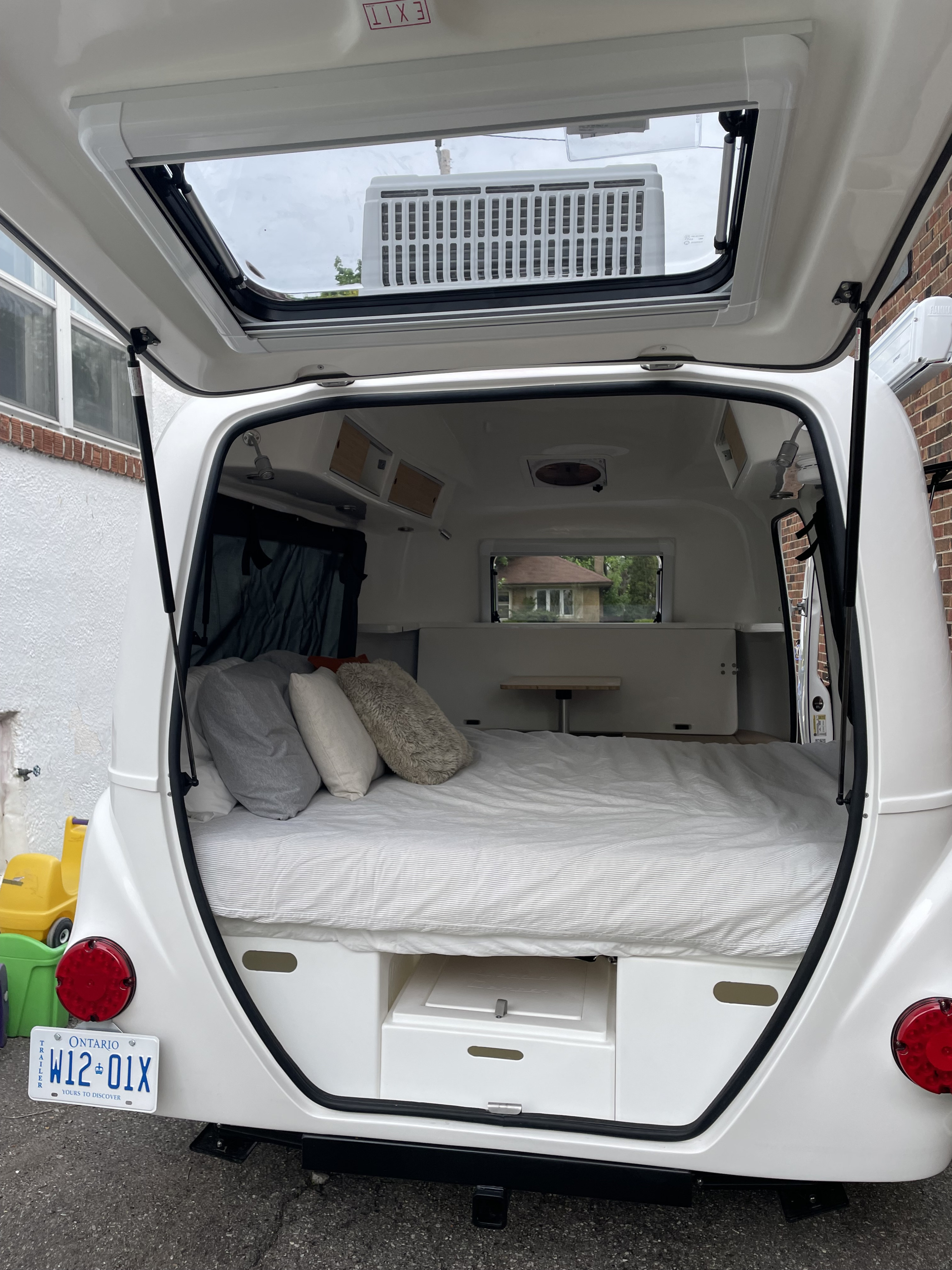 Cozy rv rental interior: a comfy bed, storage, ceiling fan, and open hatch await your next road trip adventure.. Happier Camper HC1 2022