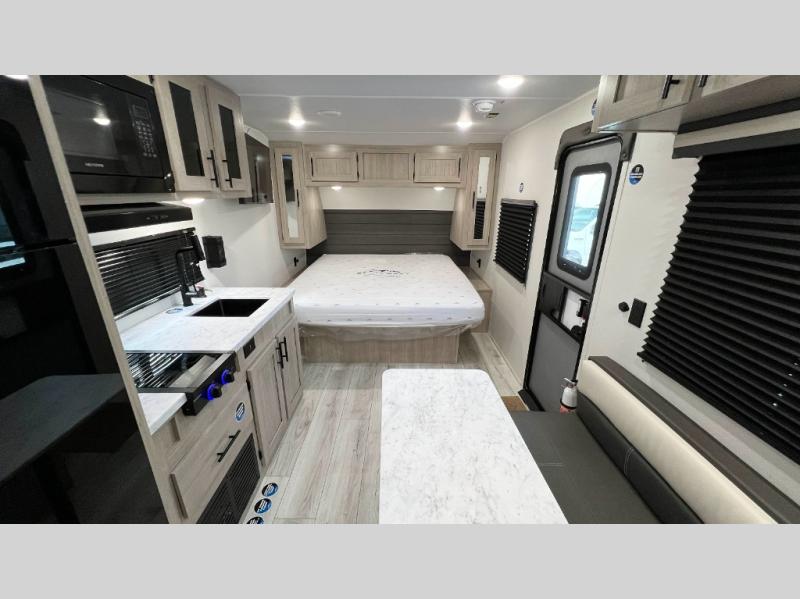 RV rental interior: kitchen with microwave & stove, a bed with overhead cabinets, and a dinette. Compact & modern.. Della Terra 250QB 2026