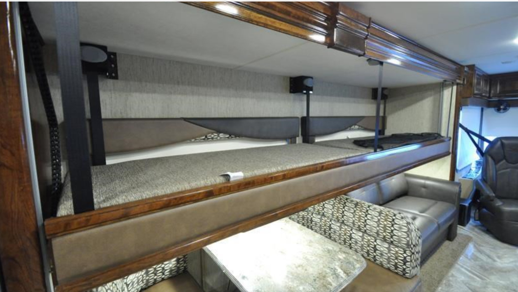 This RV rental interior features drop-down bunk beds above a dinette, offering versatile living and sleeping space with additional seating.. Coachmen Sportscoach 2018