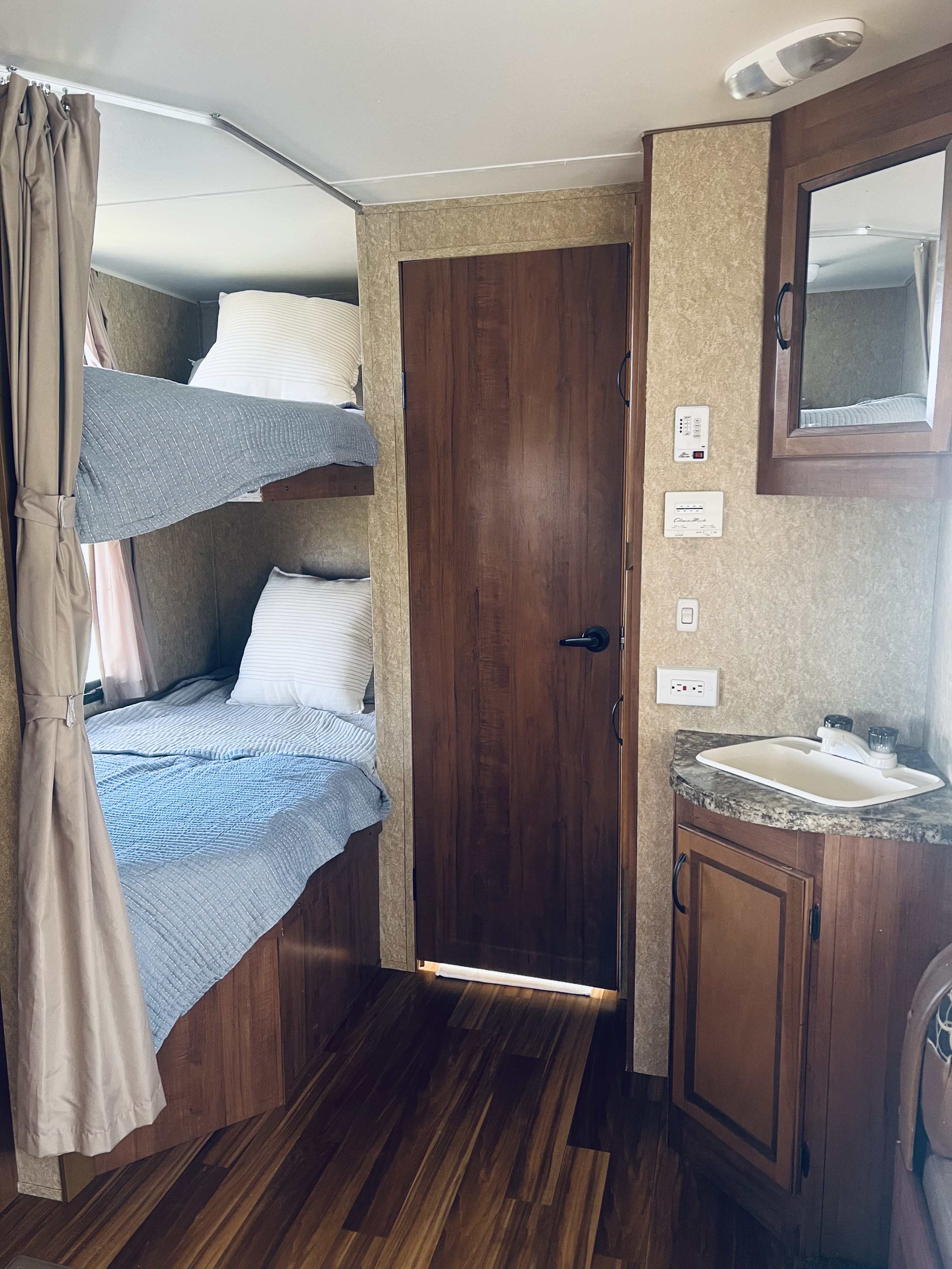 Inside an RV rental: cozy bunk beds, privacy curtains, and a compact sink area.. Gulf Stream Kingsport 2013