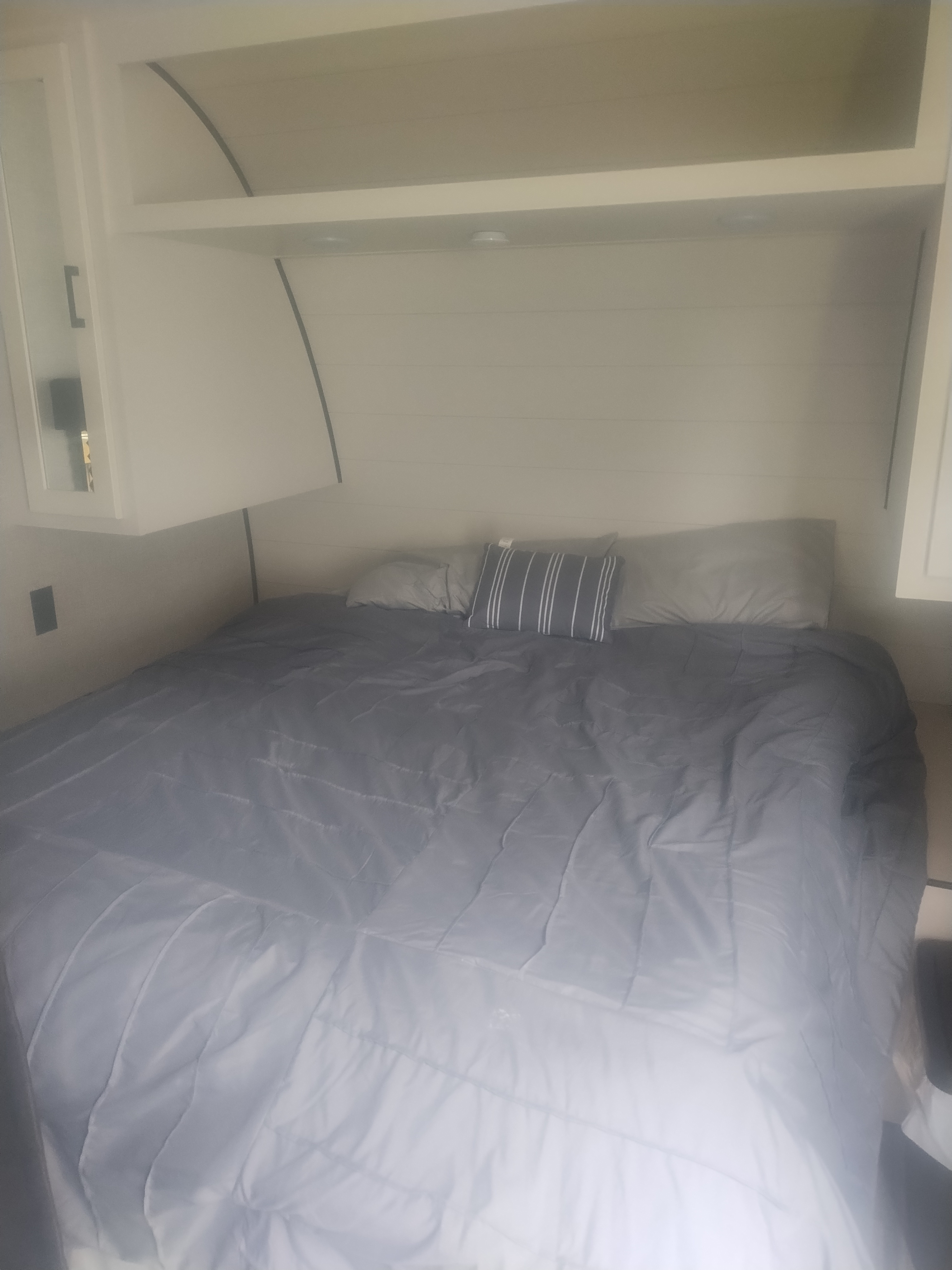 Cozy RV rental bedroom featuring a grey bed with pillows and white overhead storage, perfect for a comfortable sleeping area.. Jayco Jay Flight SLX 2025