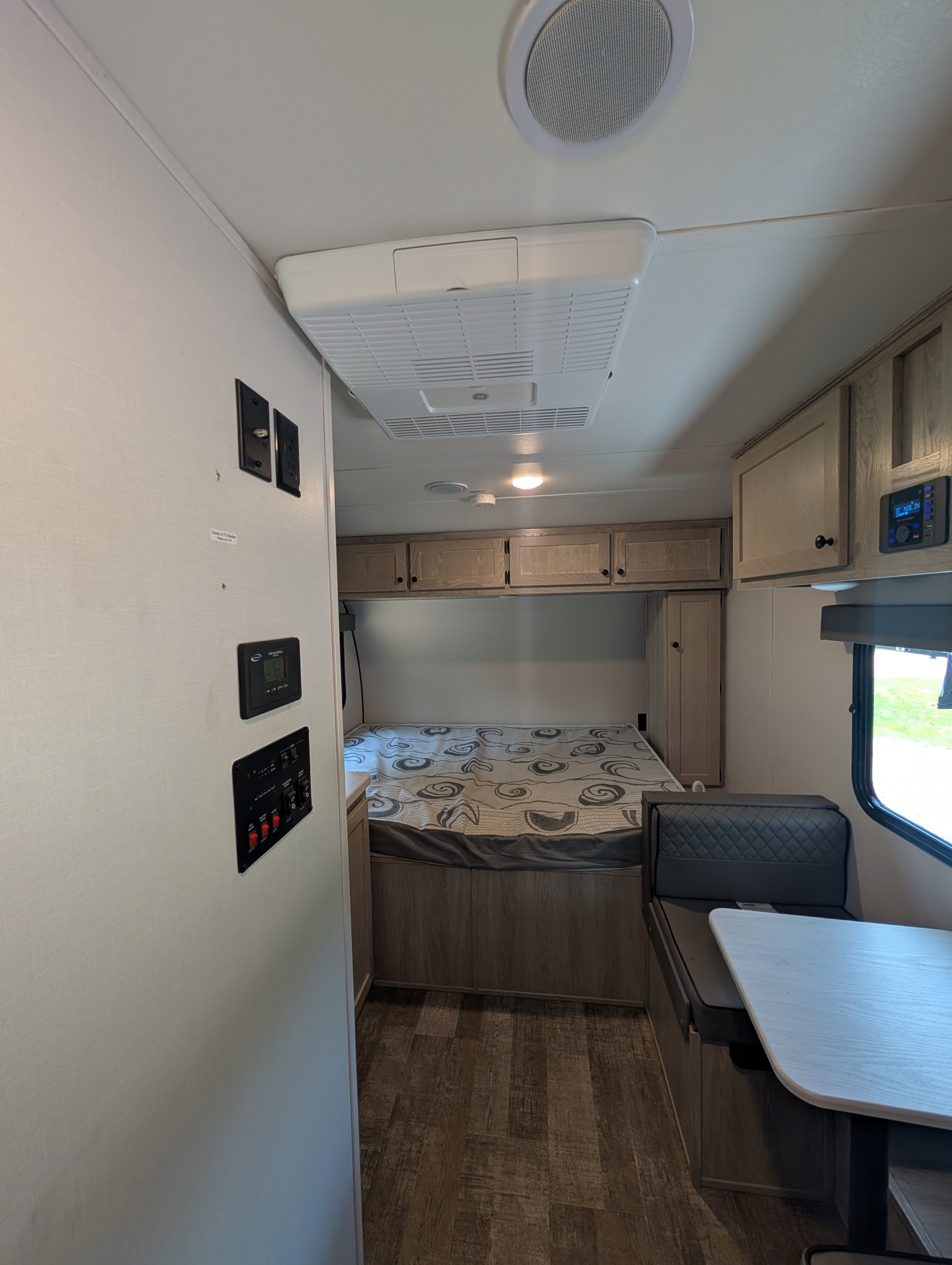 Inside this modern rv rental: a compact bedroom with overhead cabinets, a dinette, and essential controls for your trip.. Riverside RV Xplorer 2024