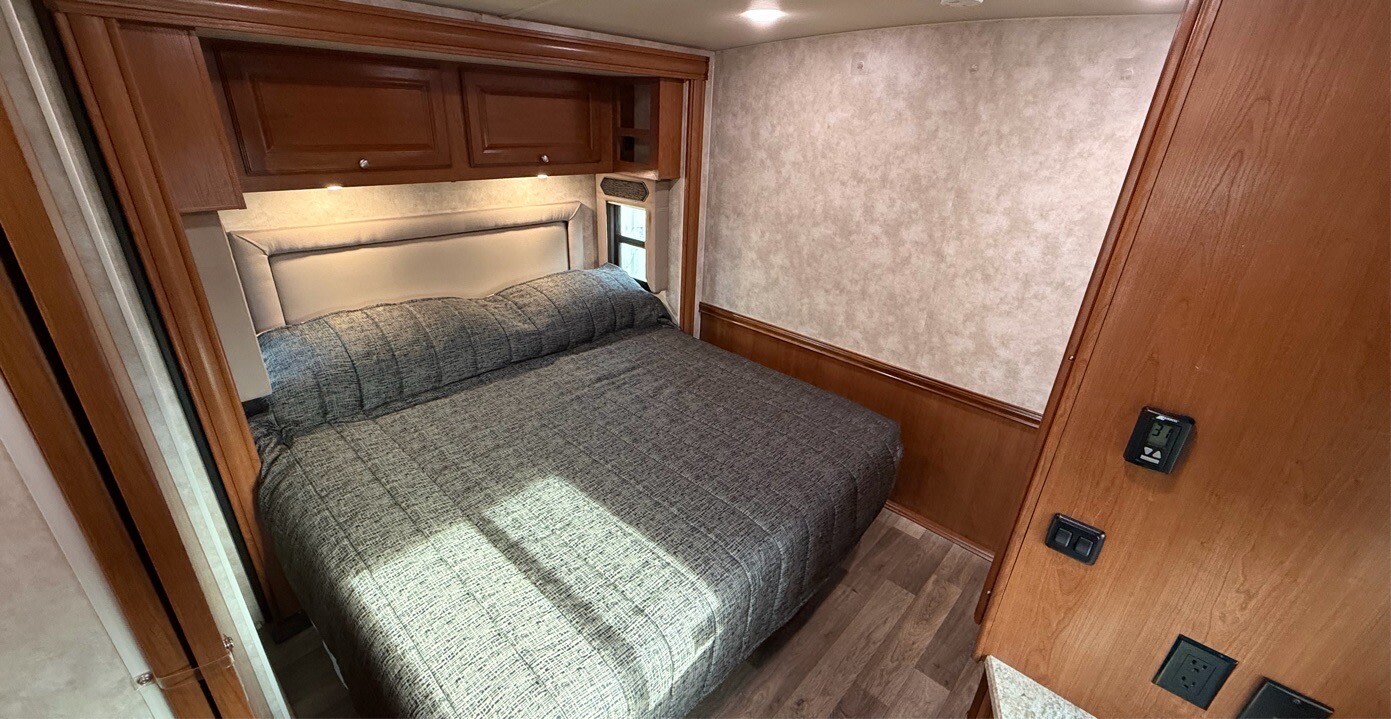 Cozy RV bedroom with a comfortable bed, overhead cabinets, and climate controls. Perfect for your next RV rental adventure!. Winnebago Adventurer 2020