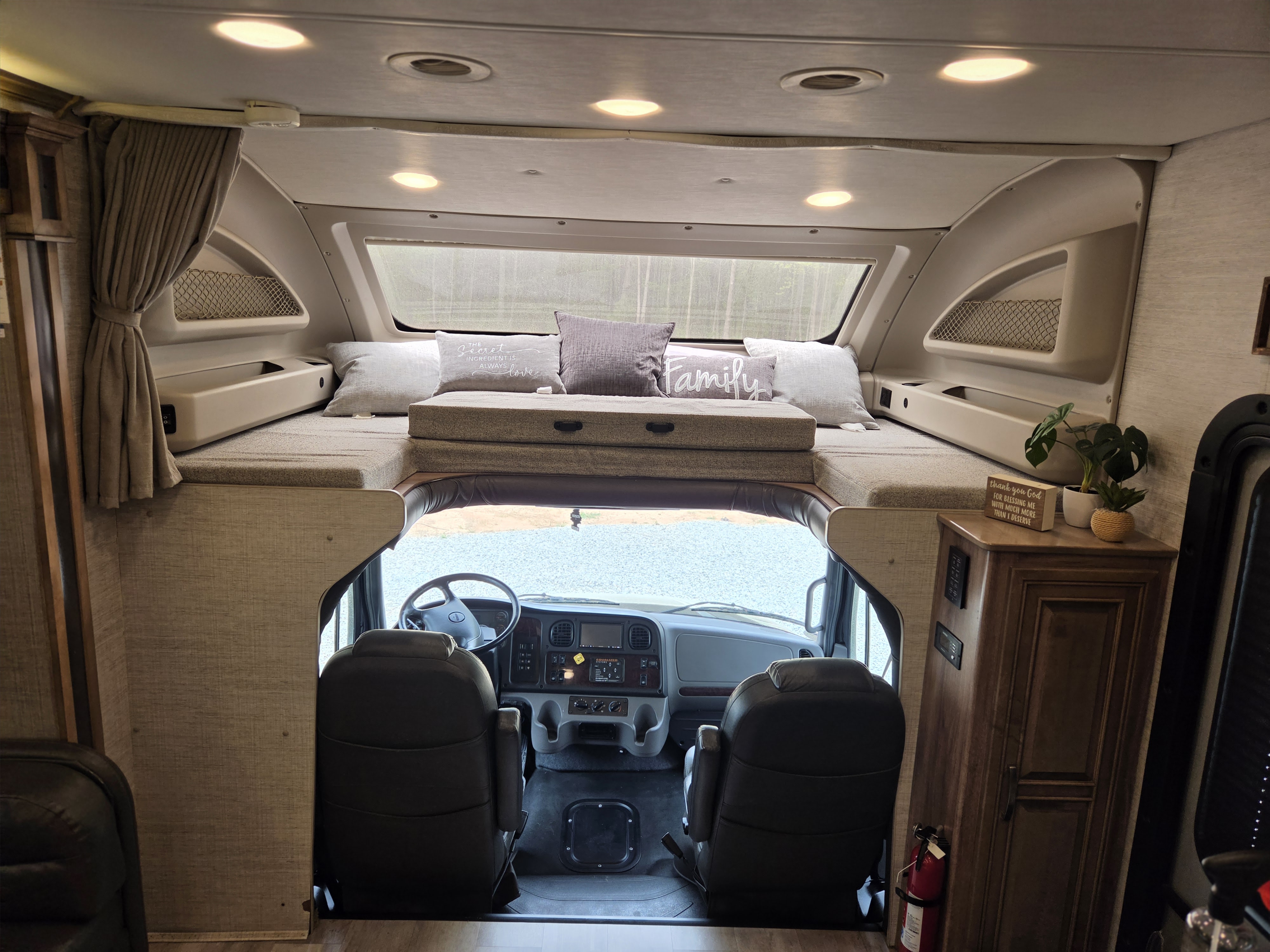 View inside a modern rv rental: the cab-over bunk with pillows and front cockpit area, detailed for travel comfort.. Jayco Seneca 2021