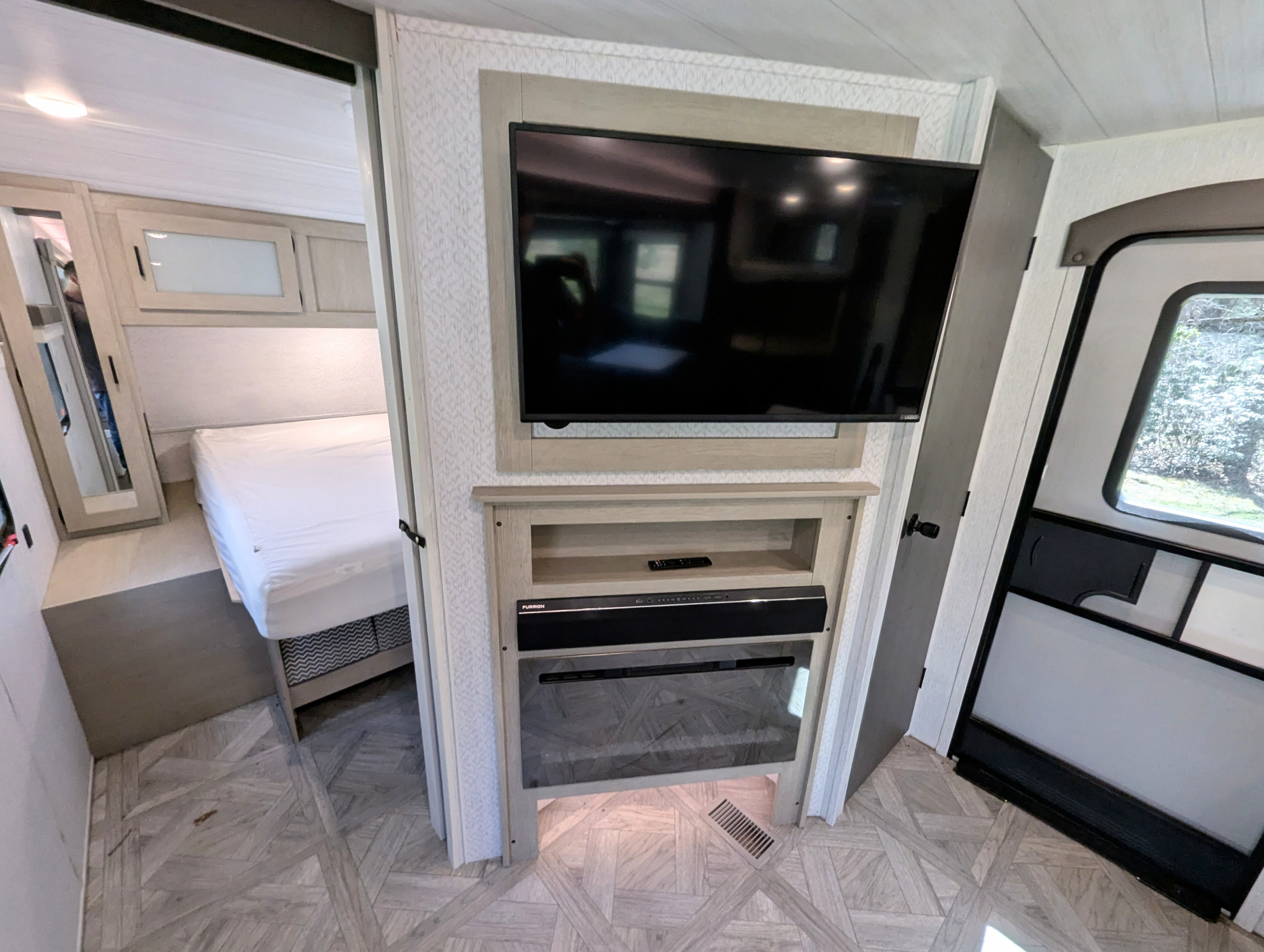RV rental interior: modern living space with TV, electric fireplace, soundbar, and a glimpse of the bedroom.. Forest River Wildwood 2023