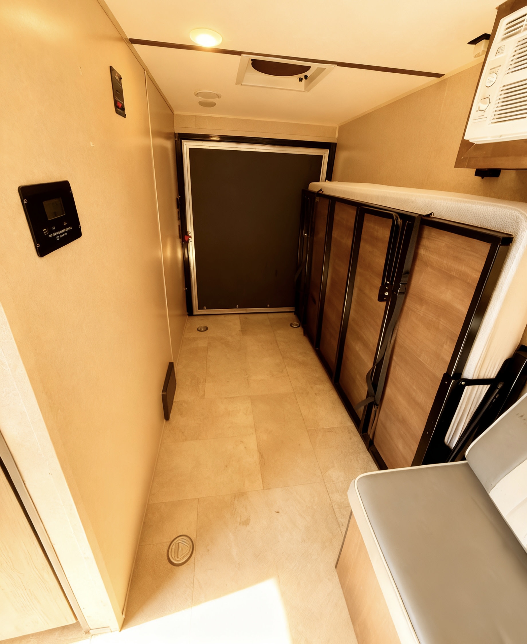 Inside an RV rental: a versatile garage space with a folded bunk bed, control panels, seating, and a rear ramp door.. Sunset Park & Rv Inc. Toy Hauler 2022