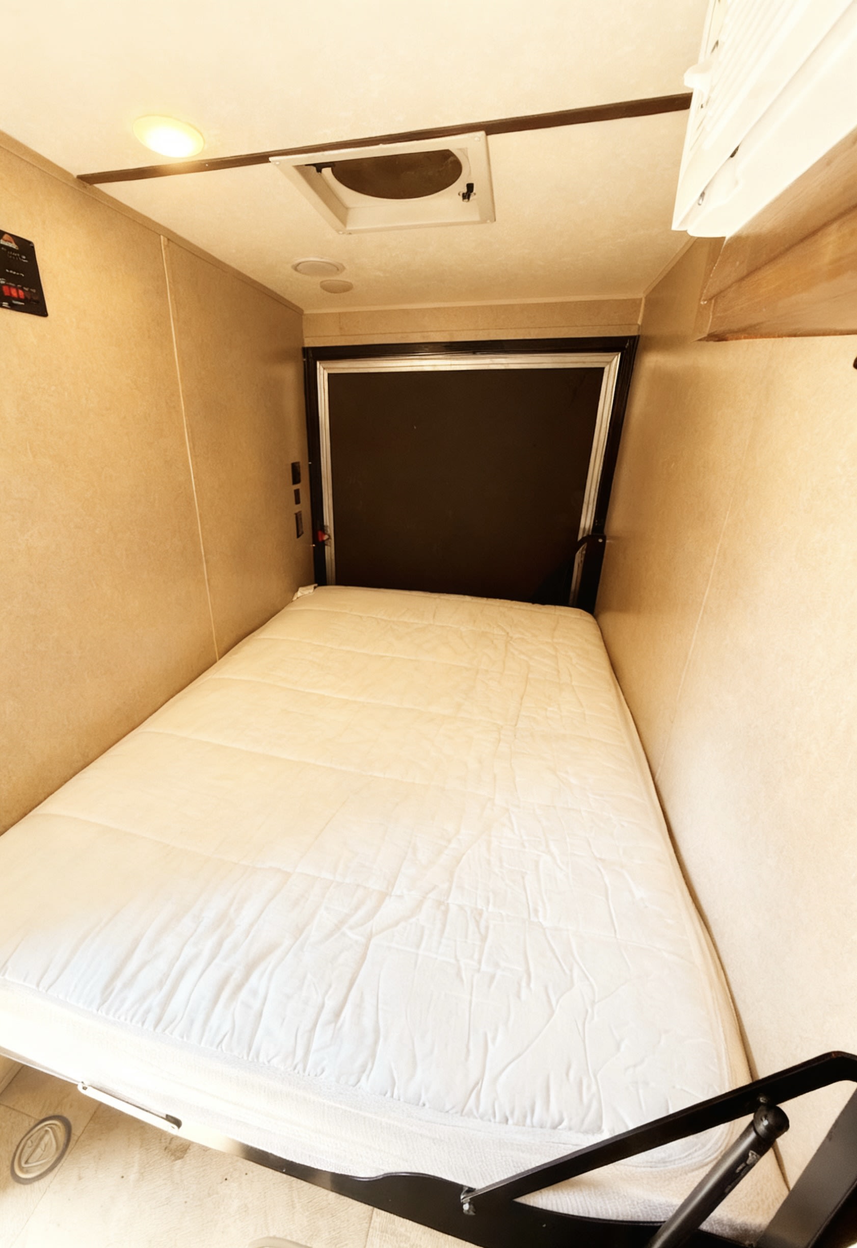 RV rental bed with white mattress. Features overhead light, vent, & compact walls for a cozy sleeping area.. Sunset Park & Rv Inc. Toy Hauler 2022