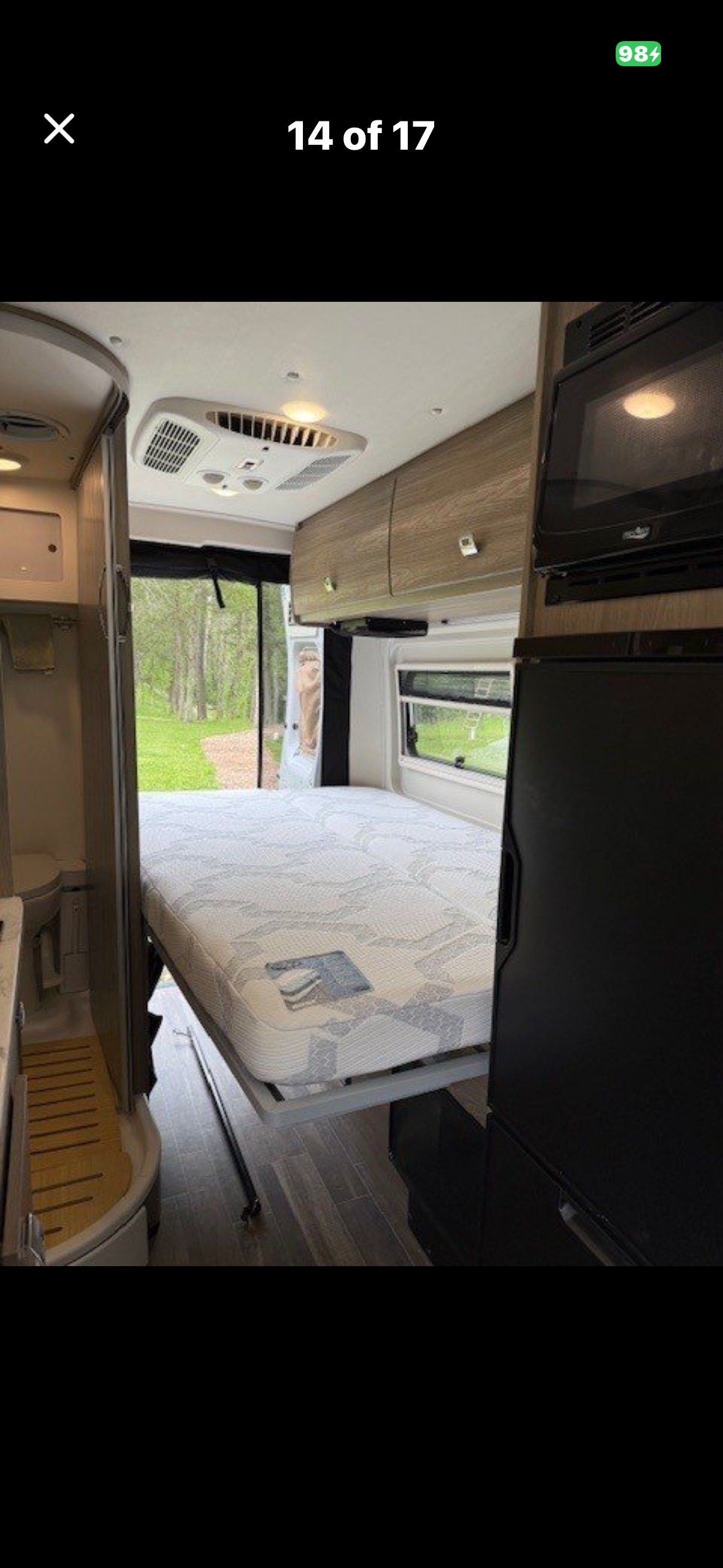 Comfortable RV rental interior featuring a fold-down bed, compact bathroom, and kitchen appliances. Perfect for travel.. Winnebago Travato 2023
