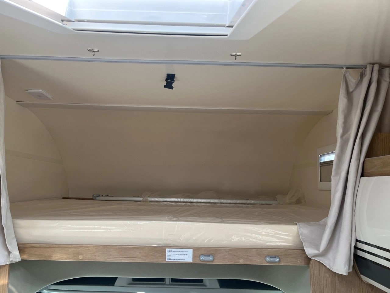 **RV rental** overcab bed: Clean, new mattress in plastic, privacy curtains, and skylight for a comfortable sleeping area.. CI HORON 77M 2023