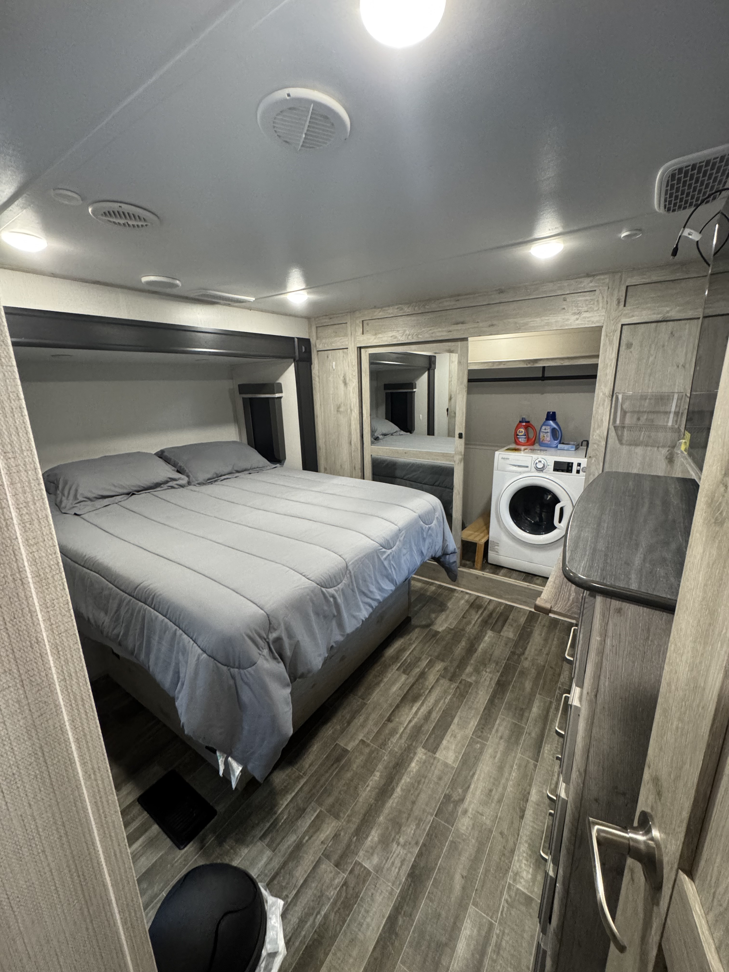 RV rental bedroom featuring a bed, in-unit washer/dryer, and modern wood-look flooring for a comfortable stay.. Keystone RV Avalanche 2021