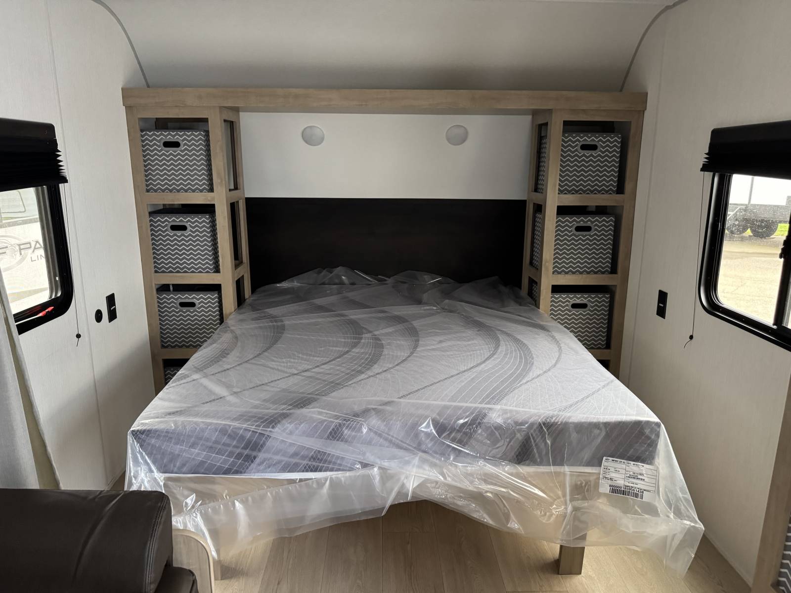 Comfortable RV rental bedroom featuring a new mattress still in plastic, built-in shelves, and decorative storage bins.. Forest River GREY WOLF 26LP 2026