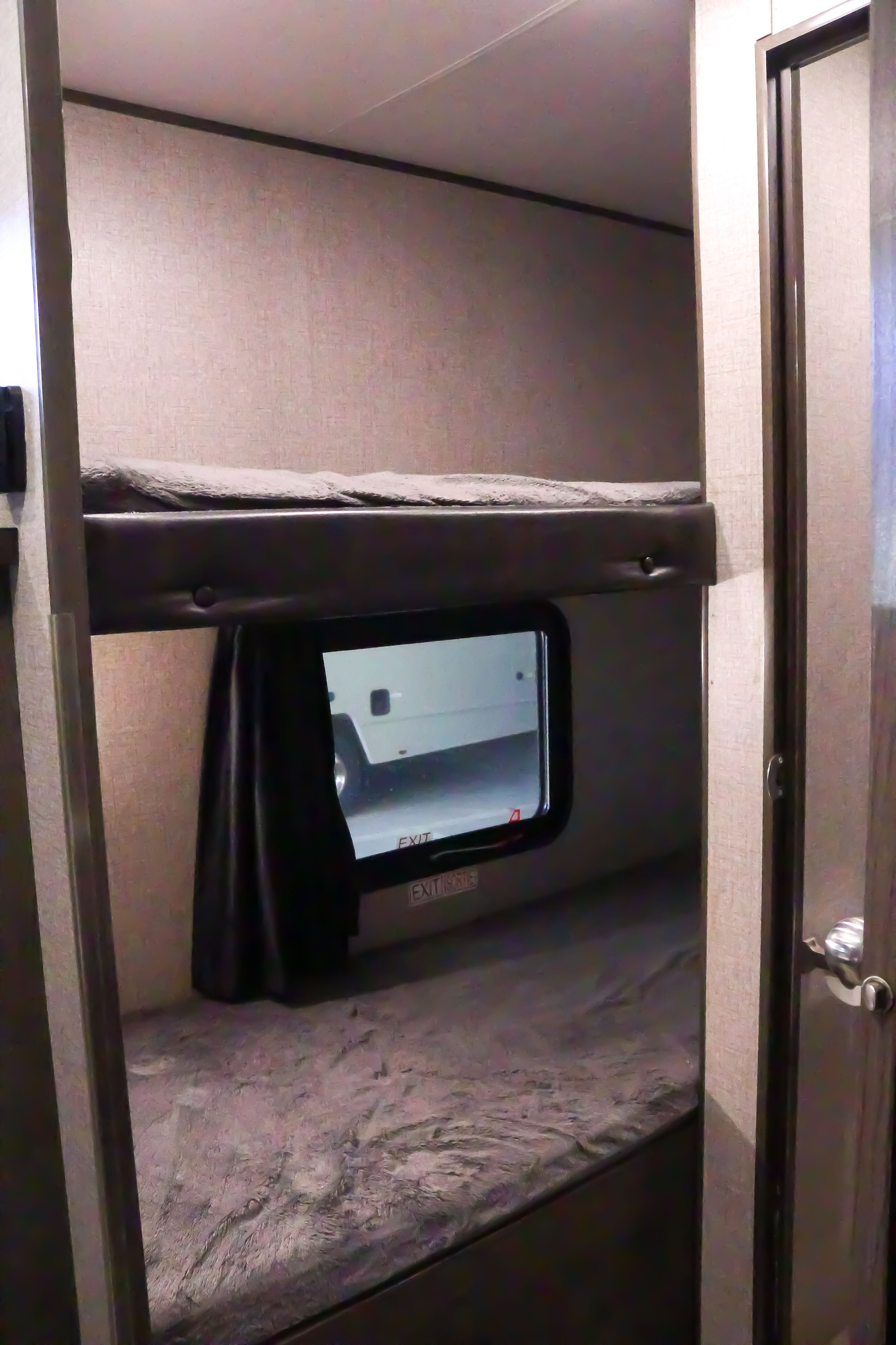 This RV rental features stacked bunk beds, with an emergency exit window visible on the lower bunk. A practical sleeping space for travel.. Jayco Baja 2021