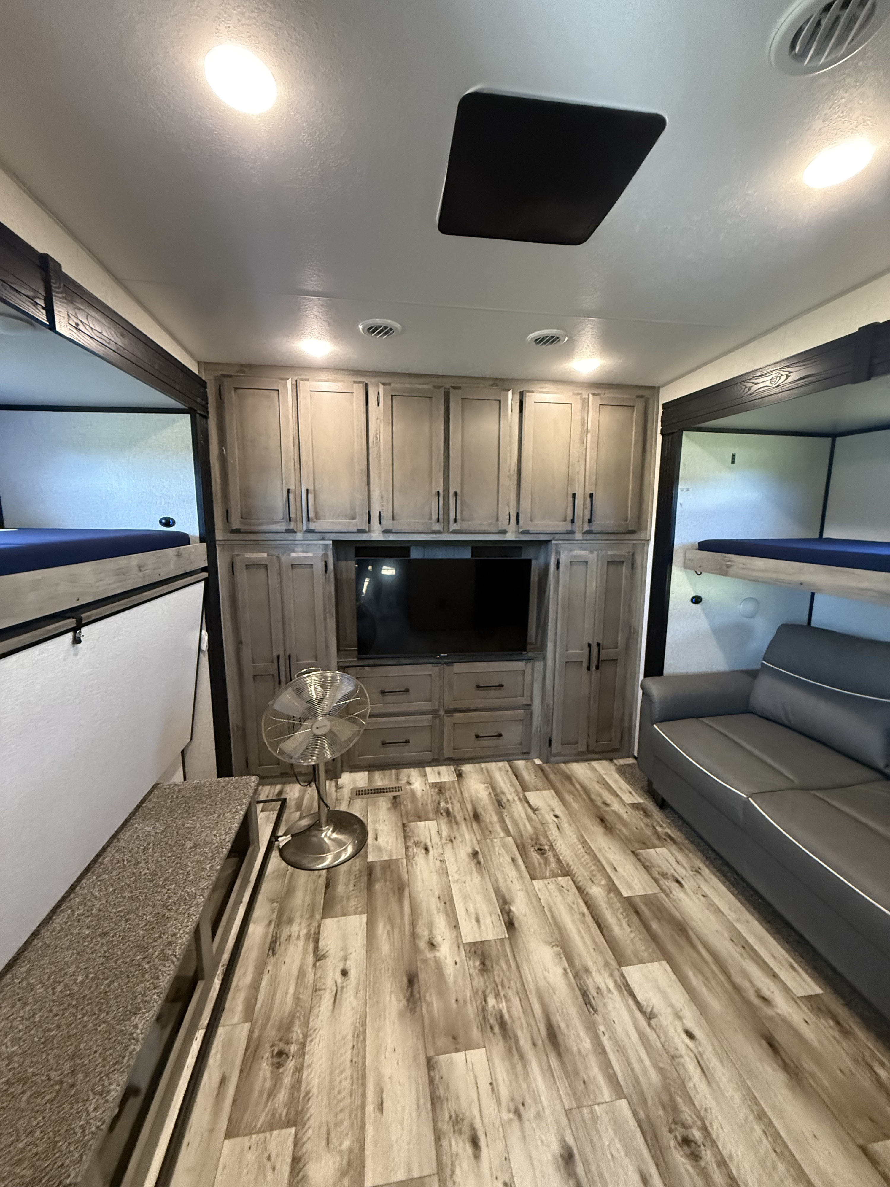 Spacious rv rental interior featuring bunk beds, sofa, TV, built-in storage, and modern wood-look flooring.. Durango Durango Fifth Wheel 2022