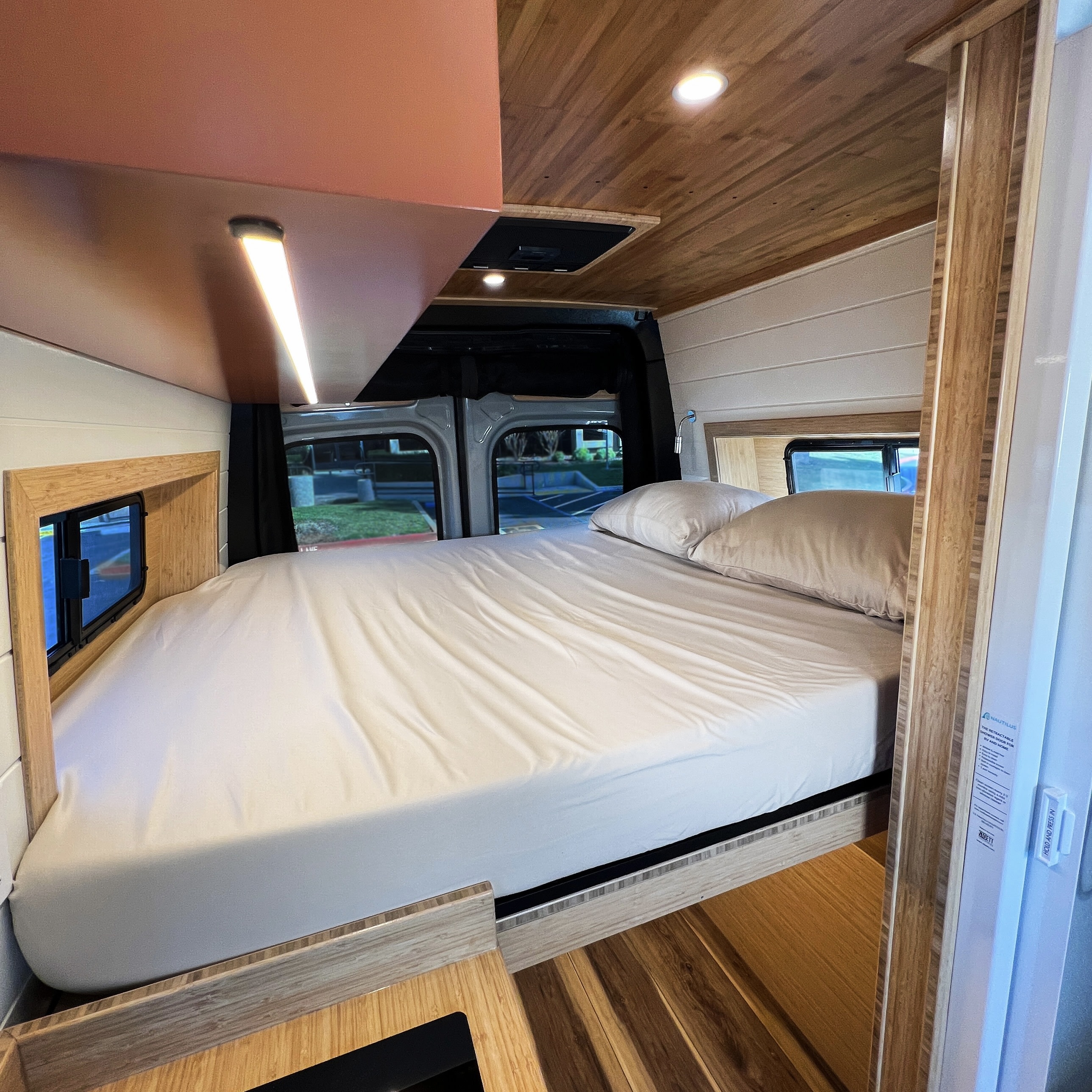 A clean, modern RV rental bedroom with a large bed, sleek wood interior, and smart lighting for comfortable travel.. Mercedes-Benz Sprinter 2026