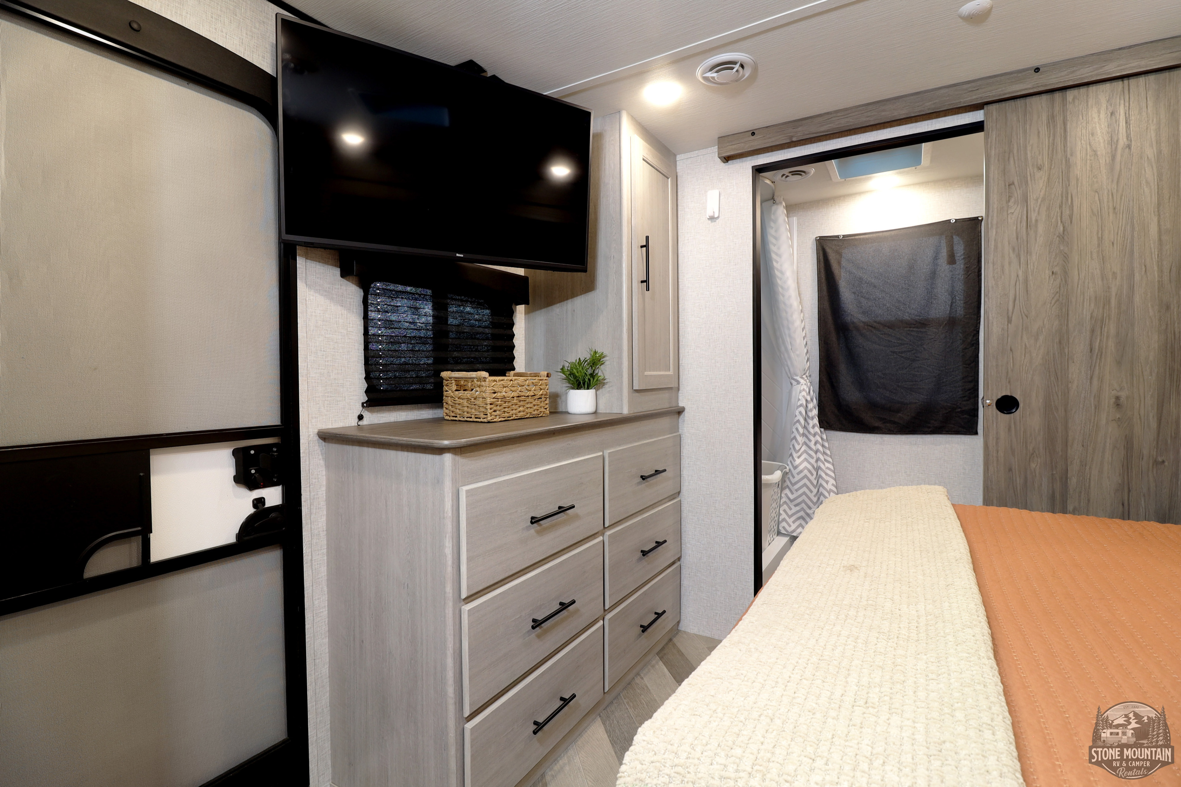RV rental: Interior of a comfortable bedroom featuring a TV, dresser, and private bathroom access.. Crossroads RV Zinger 2024