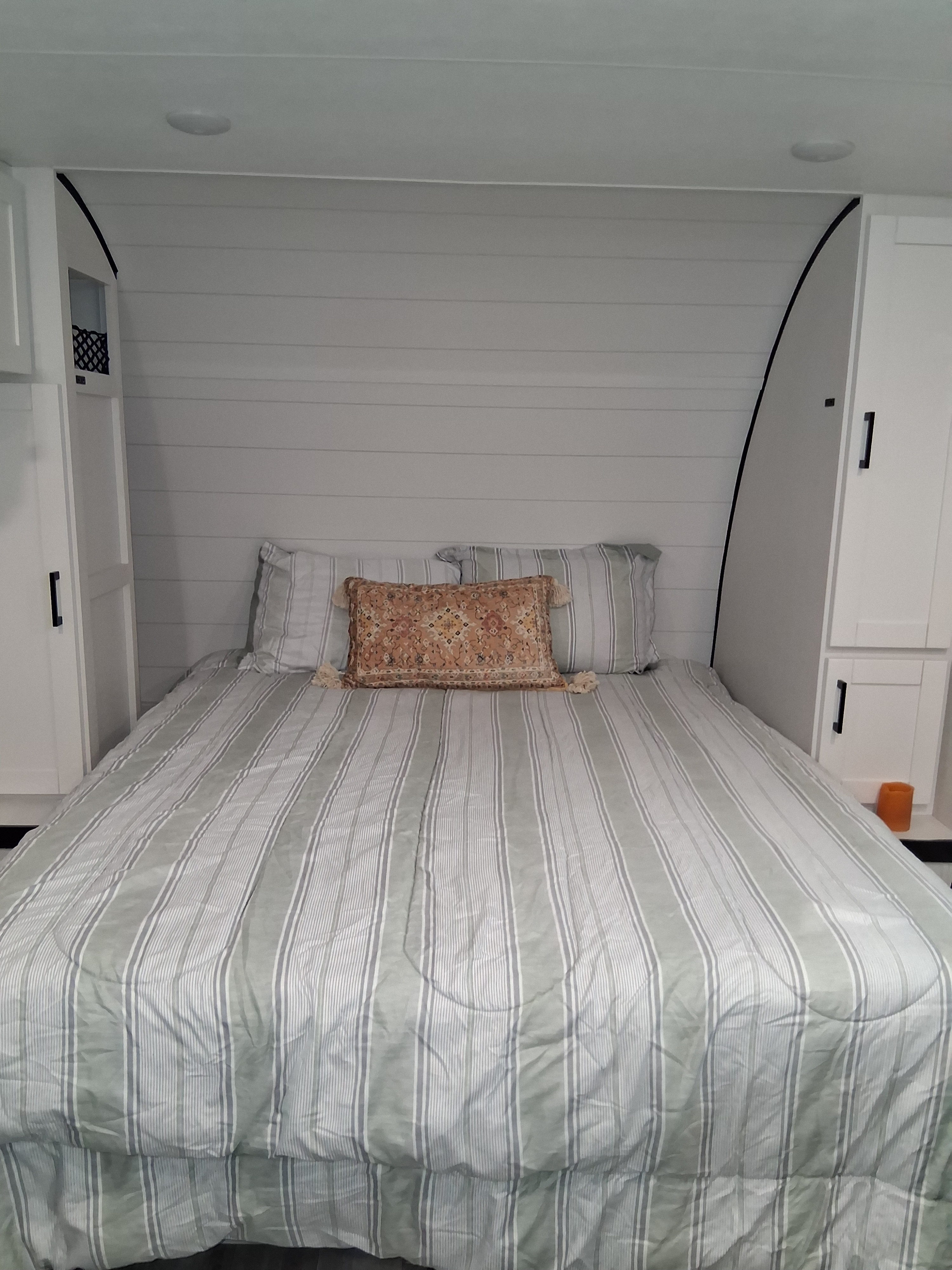 Cozy RV rental bedroom with shiplap headboard, striped bedding, a patterned pillow, and built-in white cabinets.. Oliver Travel Trailers Jay Fligh SLX 2026