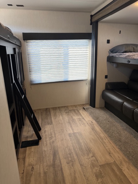 Inside this RV rental: A bunkhouse with two bunk beds, a leather sofa, and wood-look flooring. Perfect for family trips.. Forest River Cherokee Grey Wolf 2022