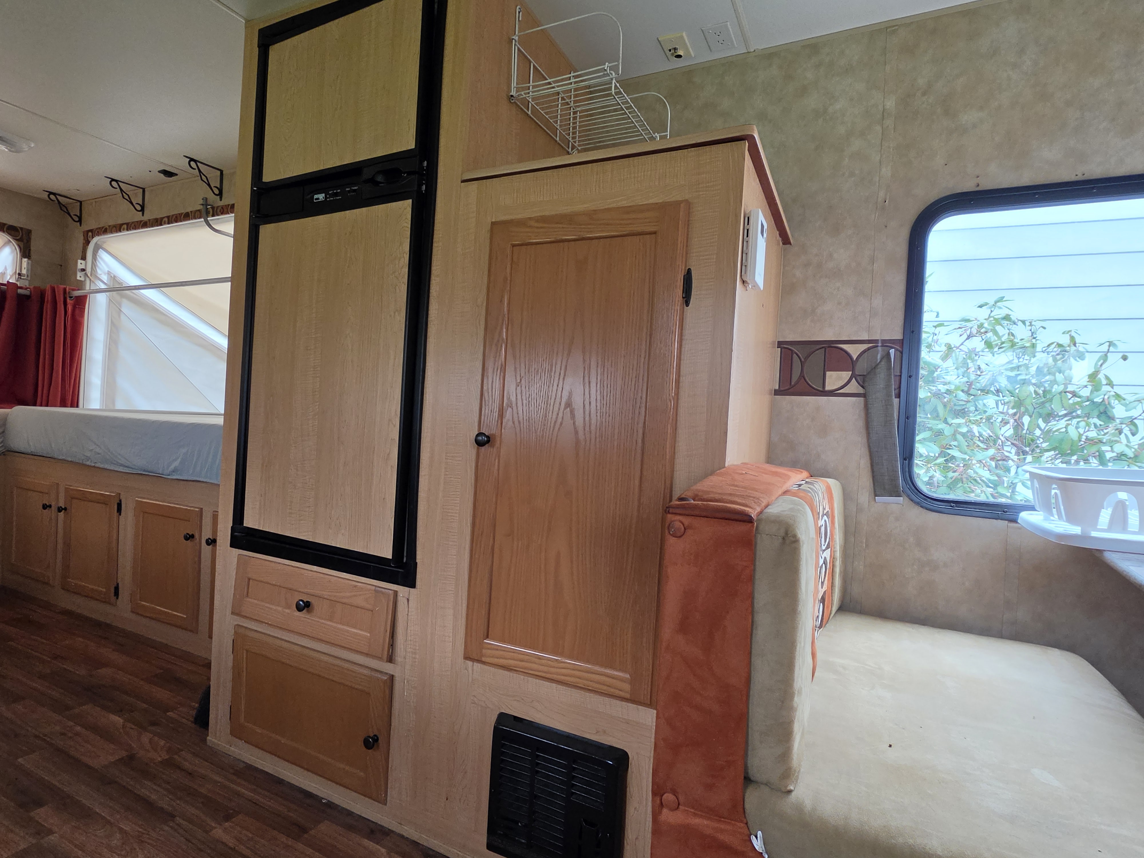 Inside an RV rental: compact fridge, wood cabinets, dinette, and bed area.. Thor KZ Coyote Hybrid 2009