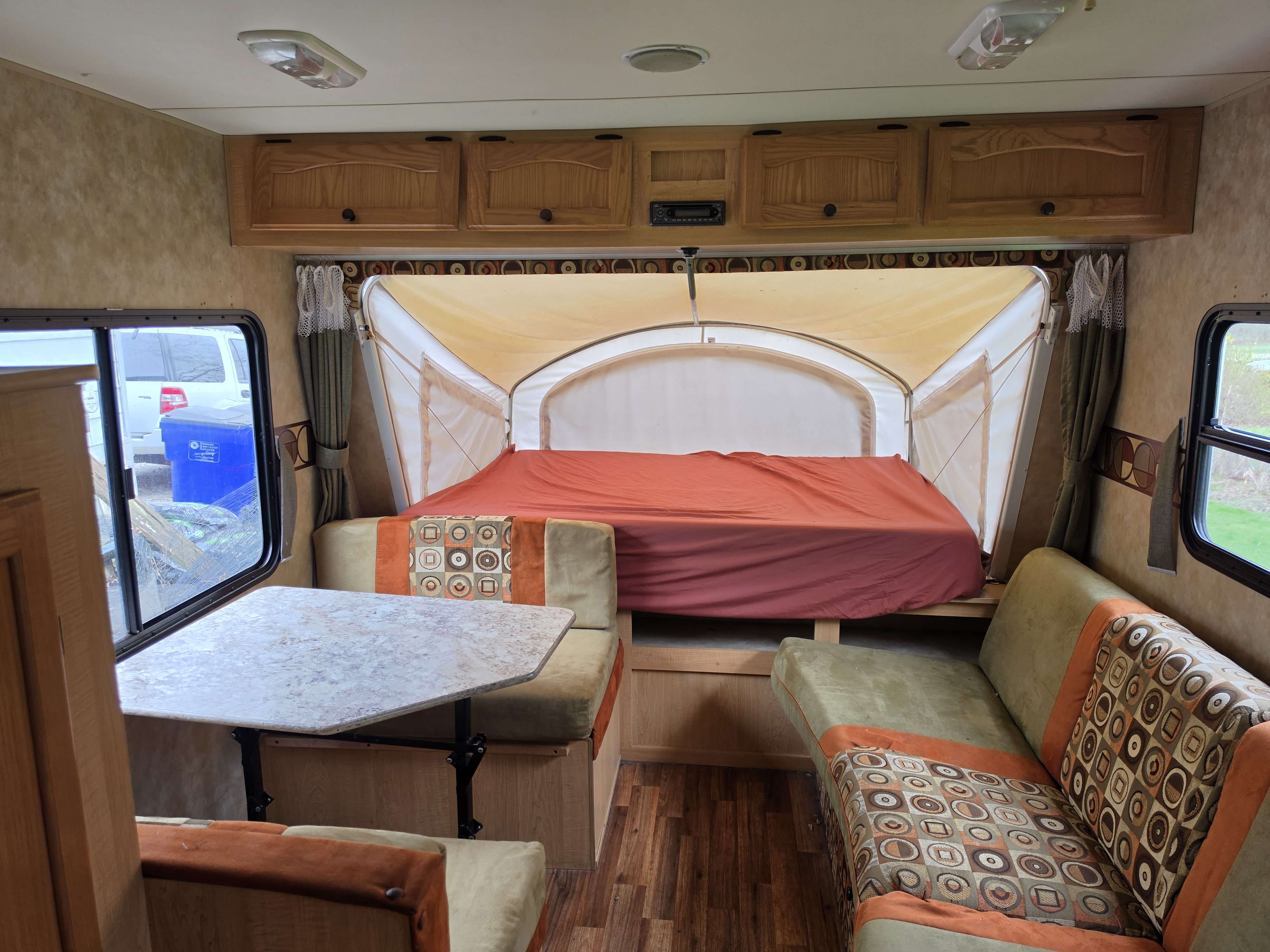 Cozy RV rental interior with a dining area, a pop-out bed, and overhead cabinets, ideal for travelers.. Thor KZ Coyote Hybrid 2009
