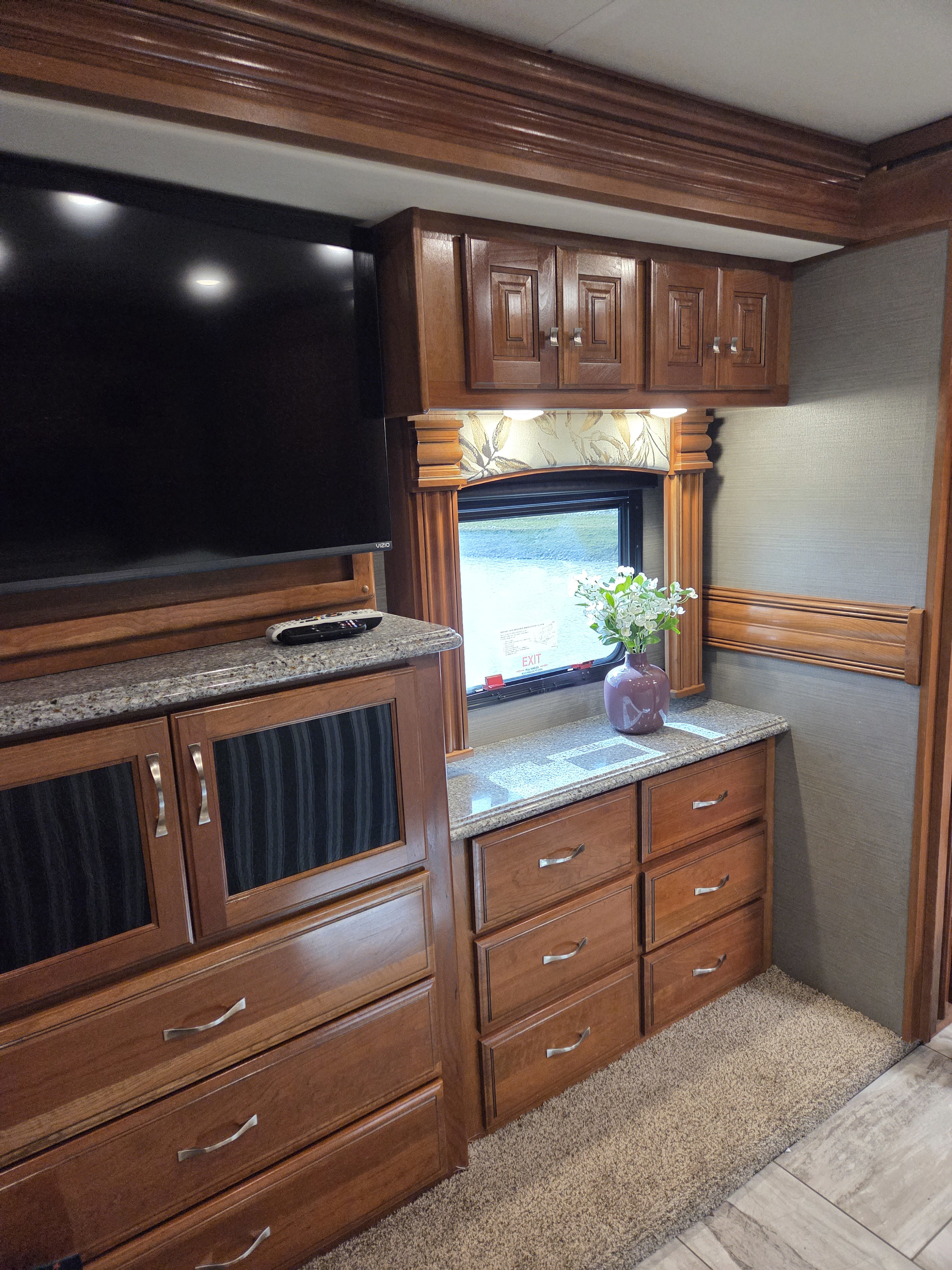 RV rental bedroom interior: wood cabinetry, large TV, granite counters, ample storage & window view for comfortable travel.. Fleetwood Discovery LXE 2018