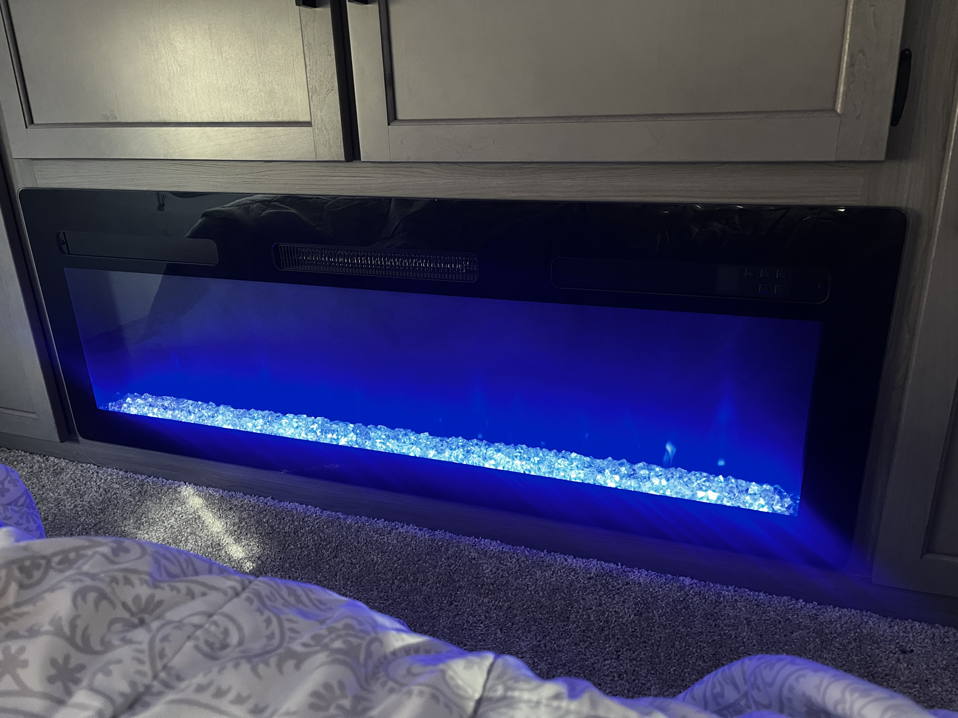 Enjoy a cozy RV rental evening! Built-in electric fireplace with striking blue lights and crystal embers creates ambiance.. Keystone RV Hideout 2024