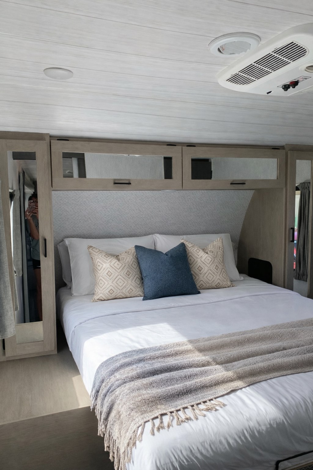 This inviting rv rental bedroom offers a comfortable bed with decorative pillows, overhead storage, and an AC unit for relaxing travel.. Forest River Salem 2024