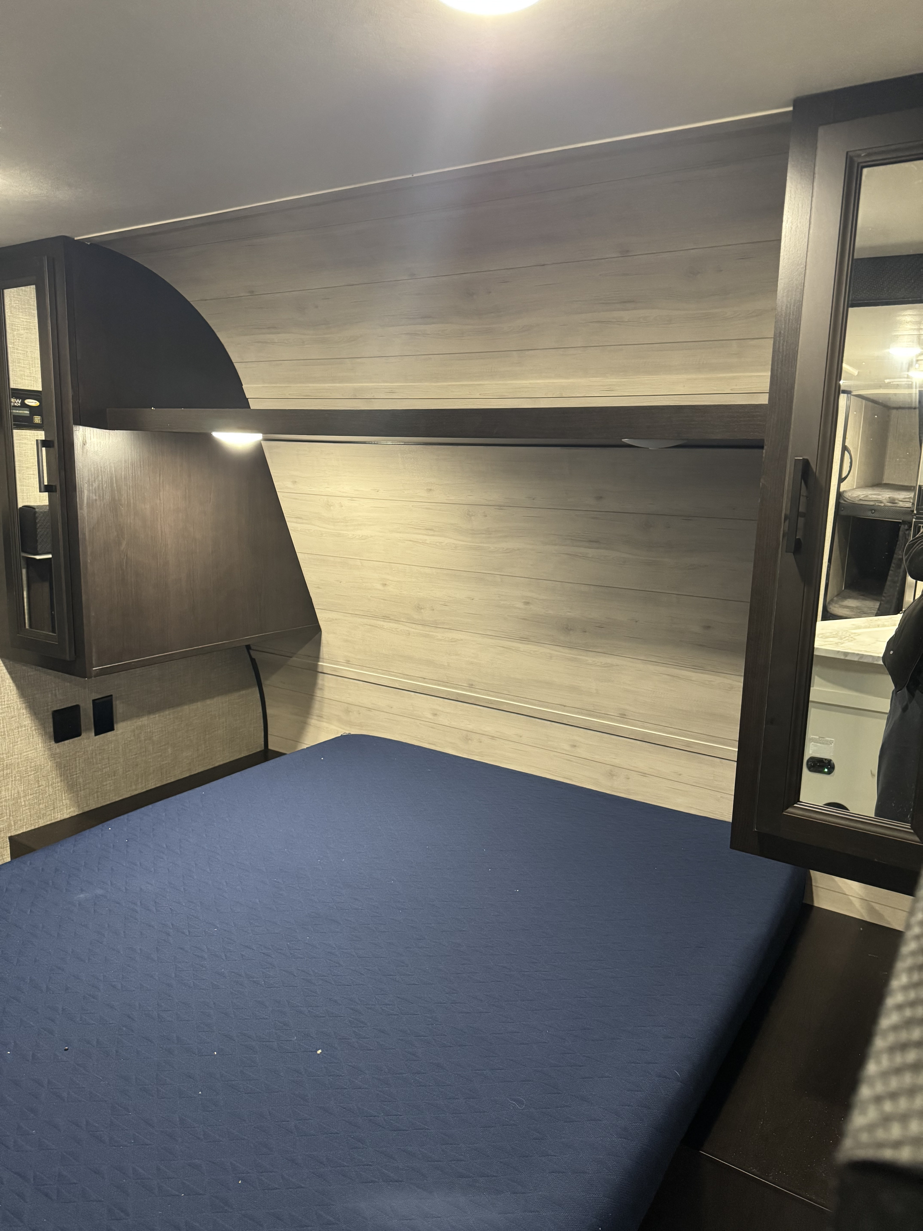 RV rental bedroom with a comfortable blue mattress, overhead storage, a reading light, and convenient power outlets.. Jayco Jay Flight SLX 2022